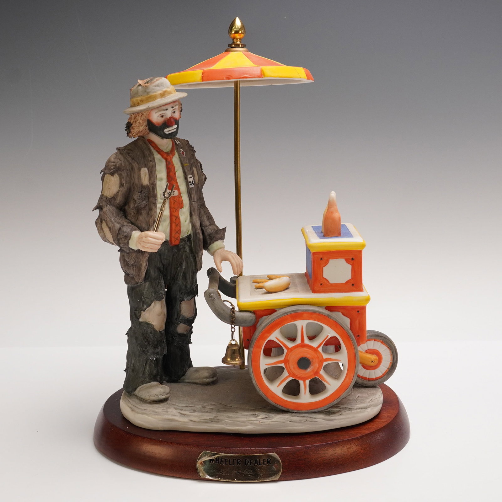 Flambro Emmett Kelly Jr. Figurine, Wheeler Dealer: Limited edition porcelain figurine from the Emmett Kelly Jr. Collection by Flambro, titled Wheeler Dealer. Features the beloved hobo clown with a colorful hot dog cart under a striped umbrella. Hand-p