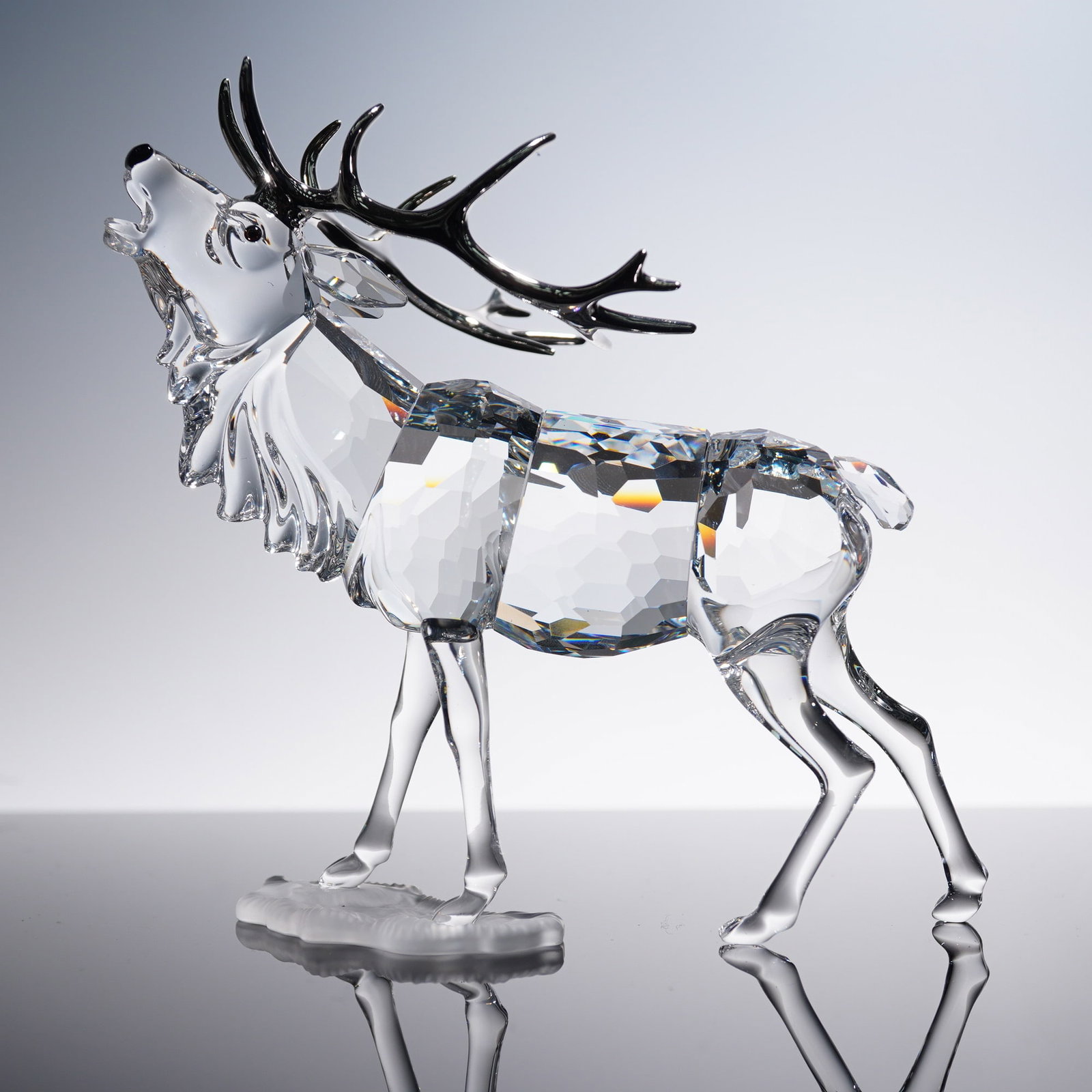 Swarovski Crystal Figurine, Stag: Swarovski crystal stag figurine featuring a detailed design with faceted body and polished antlers, standing on a frosted base. This elegant collectible showcases Swarovski's precision-cut crystal cra