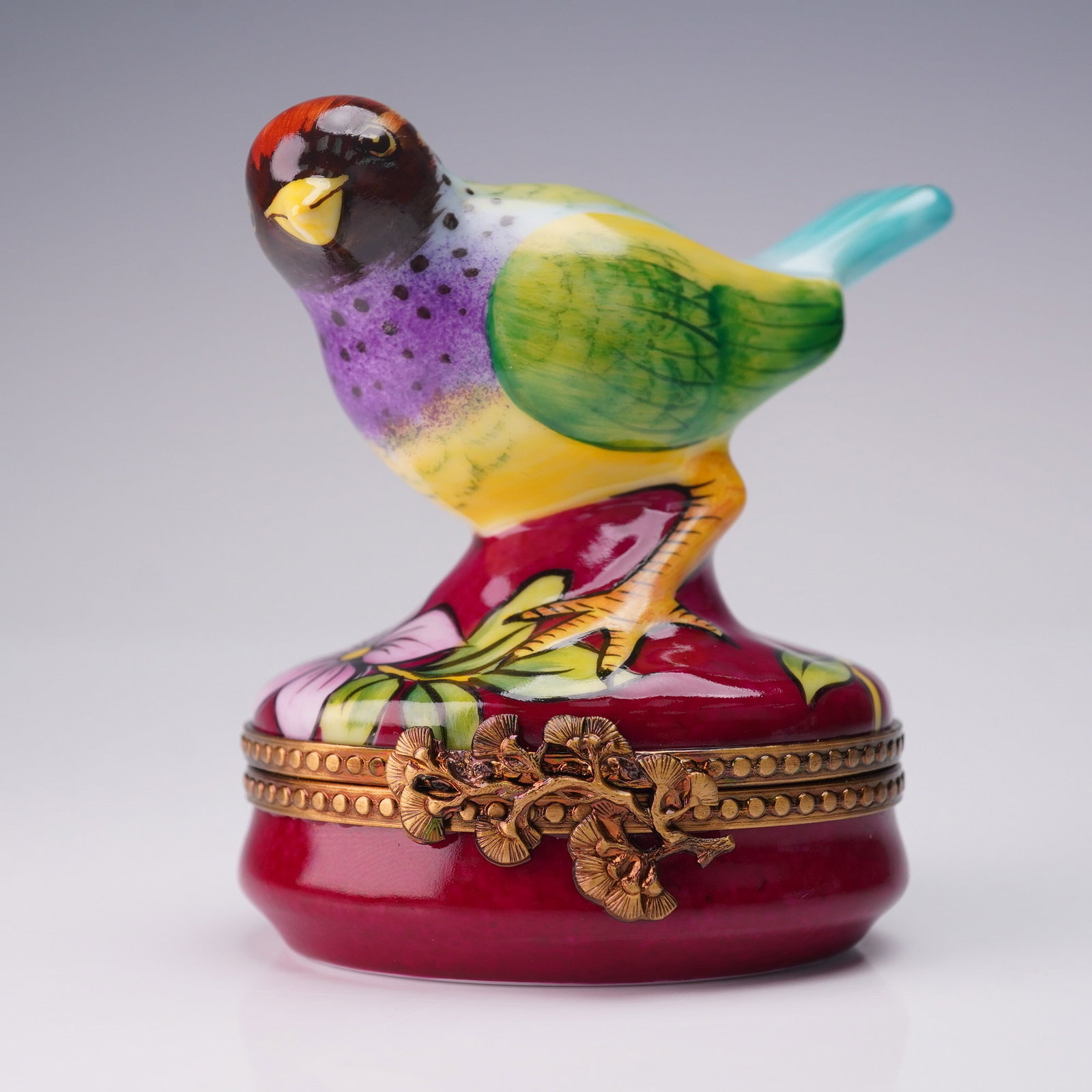 Limoges France Hand Painted Bird on Burgundy Ring Box: Vibrant Limoges France ring box featuring a hand painted bird perched on a floral base, finished in a rich burgundy glaze. The interior reveals a delicate painted feather motif, and the base is marked