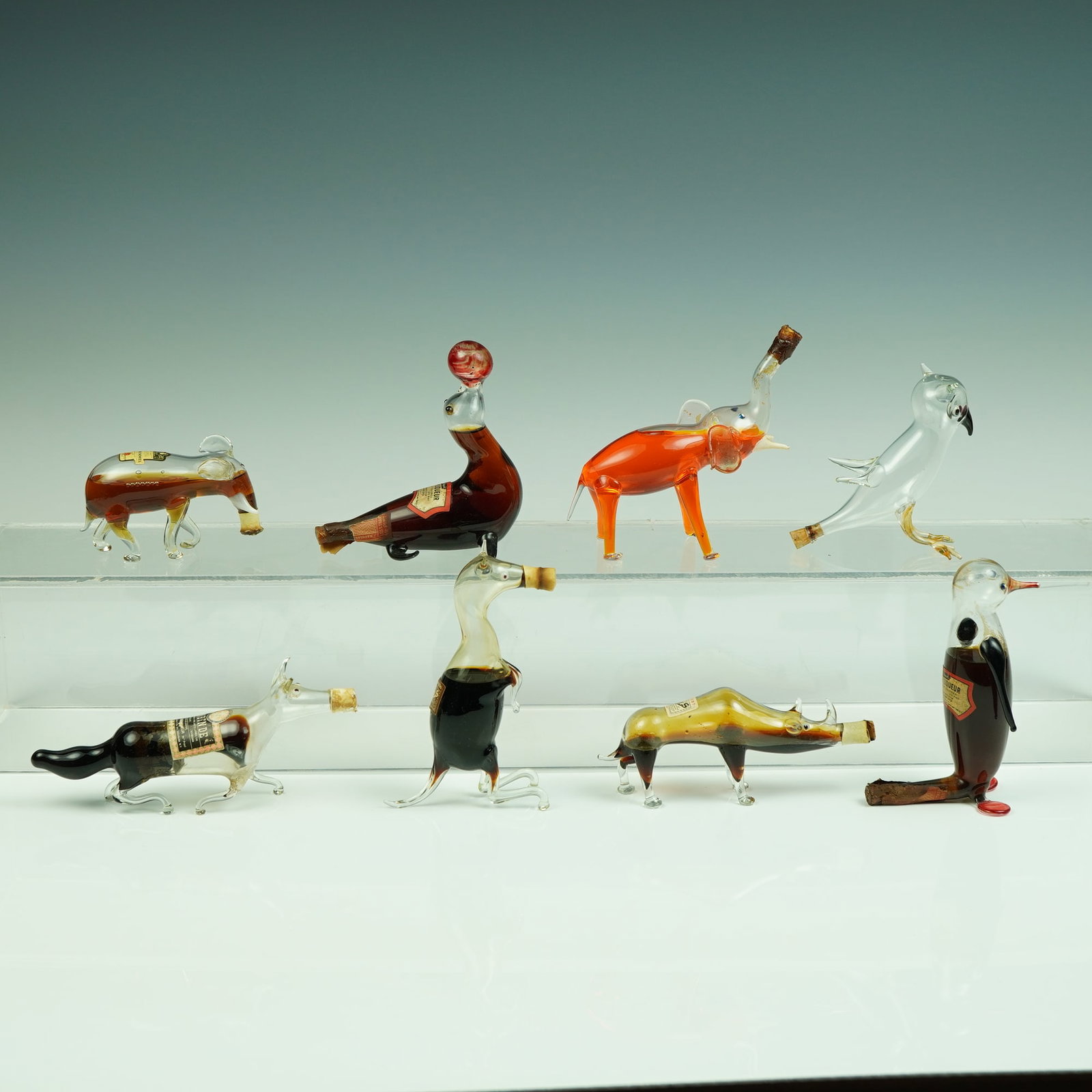 Collection of 8 Rynbende Holland Hand-Blown Glass Liqueur Bottles: A delightful and whimsical collection of eight hand-blown glass liqueur bottles, most retaining original Rynbende Holland labels and corks, each masterfully crafted in the form of various animals and 
