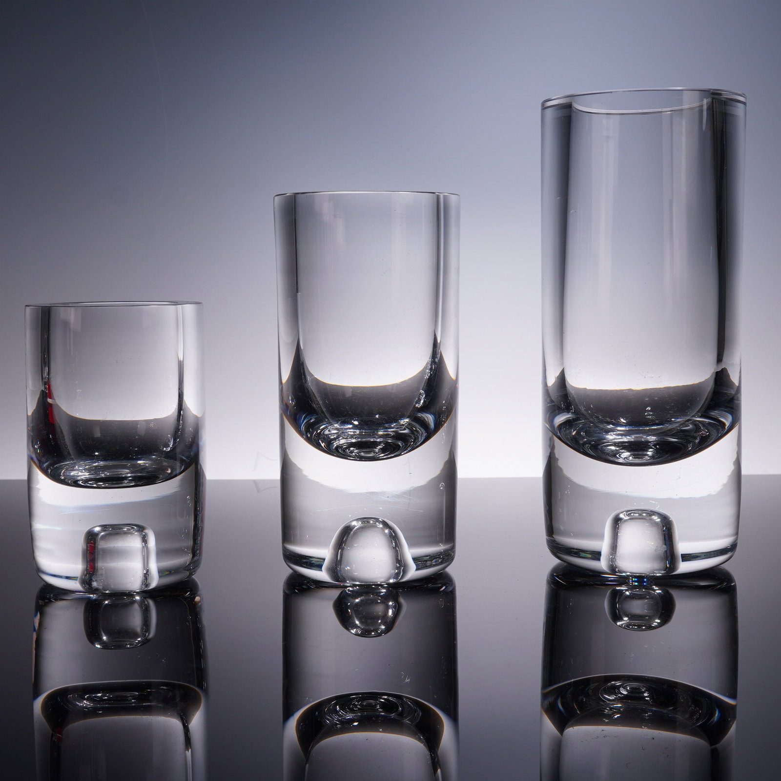 3pc Art Glass Vases Studio Ahus Swedish: Modern Swedish art glass bud vase set from Studio Ahus, featuring three clear cylindrical vases with thick bubble-inclusion bases. Each piece varies in height, with one small vase measuring approximat