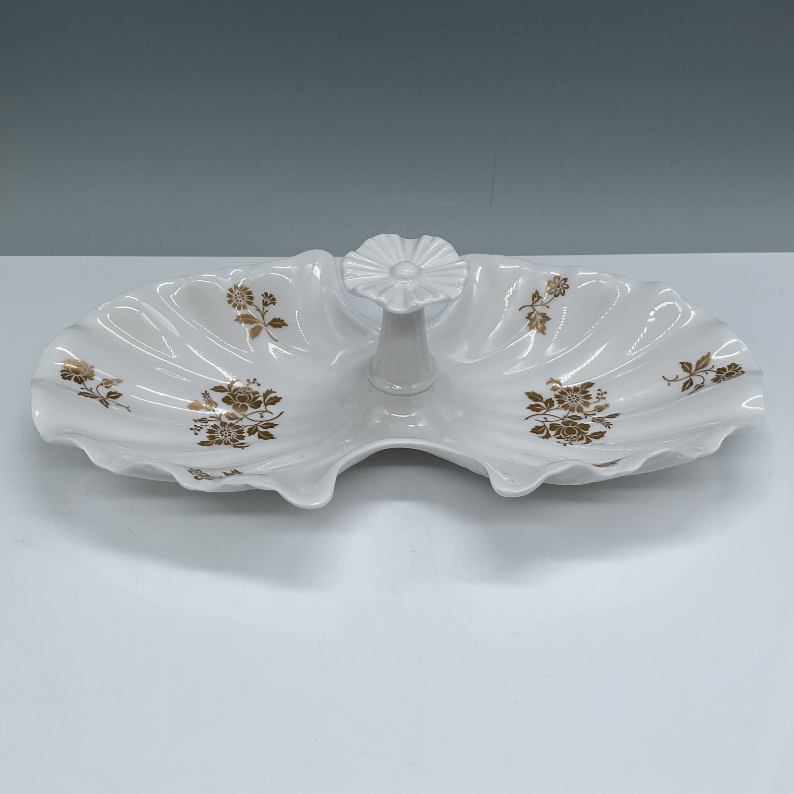 Beaumont by Spode Shell-Shaped Serving Dish: This elegant Beaumont by Spode shell-shaped serving dish features a pristine white china base with intricate gold floral accents. The central pedestal-style handle adds both functionality and sophisti