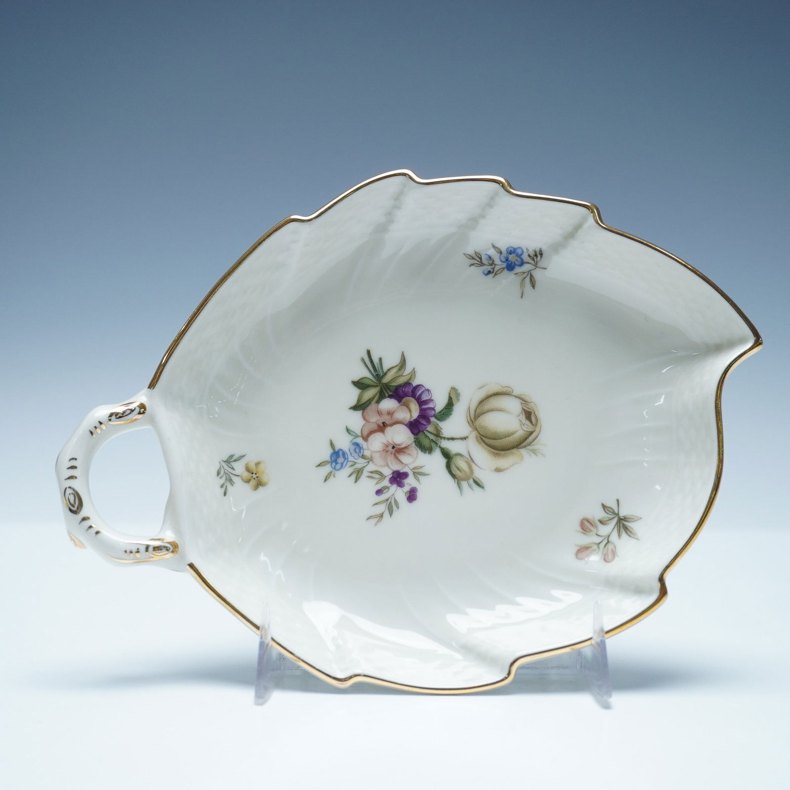 Royal Copenhagen Leaf Shape Pickle Dish, Frijsenborg: Porcelain pickle dish in the Frijsenborg pattern. The dish is shaped as a leaf with a scalloped edge and gold trim. The surface is decorated with a multicolored floral motif featuring various flowers