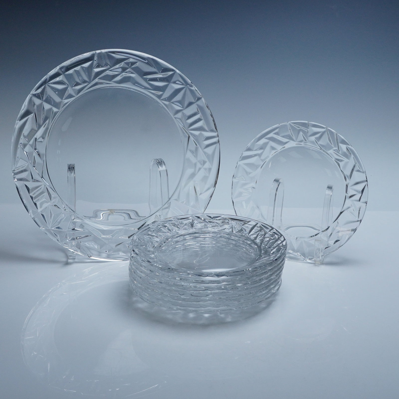 9pc Tiffany and Co Rock Cut Crystal Plates + Platter: Set of 8 Rock Cut crystal dessert plates 8" dia. and 1 Round Platter 12" dia. by Tiffany and Co, dating to the 1970s. Features the iconic midcentury geometric faceted border and smooth centers, with a