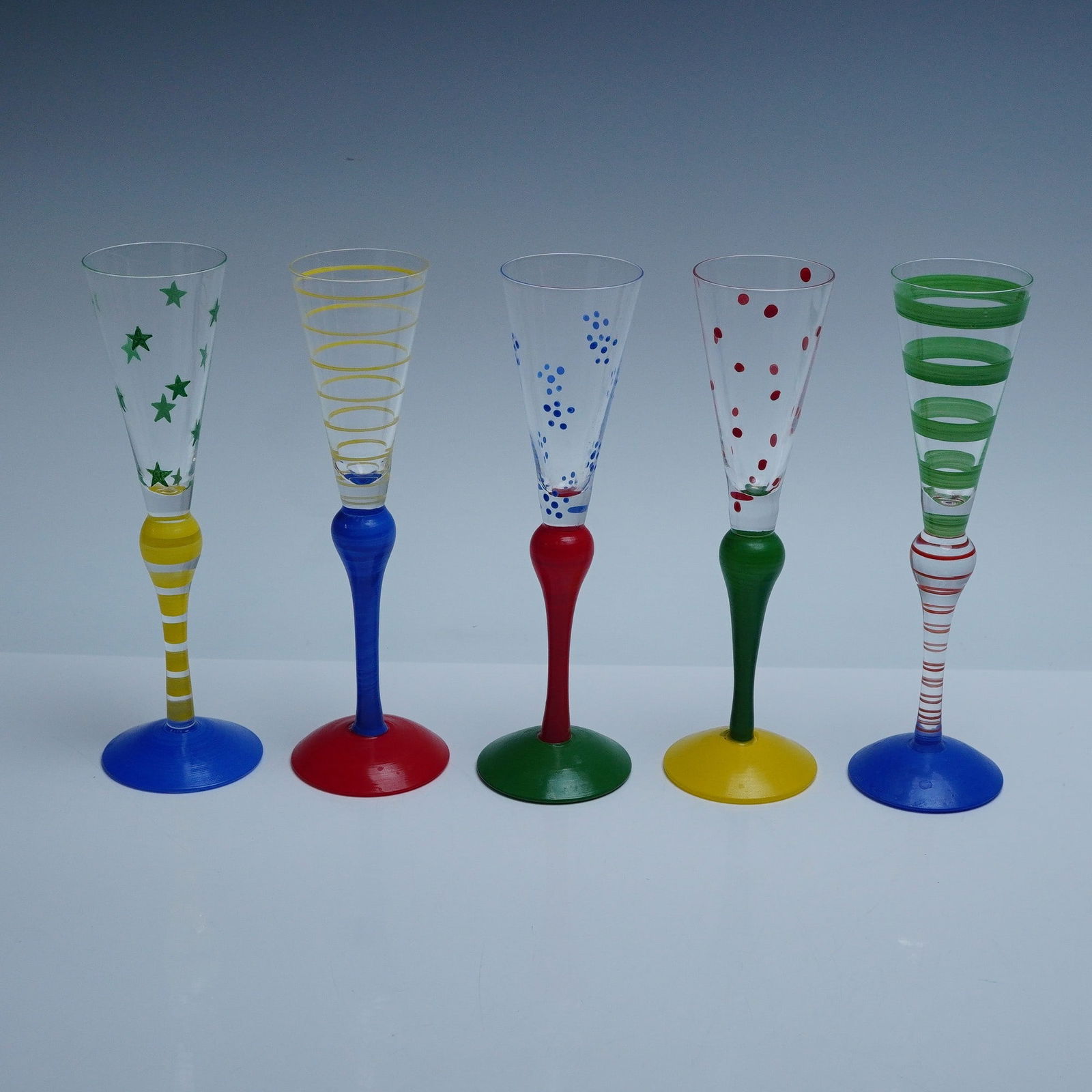 5pc Anne Nilsson for Orrefors Clown Champagne Flutes: Set of five hand-blown Clown champagne flutes designed by Anne Nilsson for Orrefors, Sweden. Each flute features a playful and vibrant combination of colored glass stems and patterned bowls, with dist