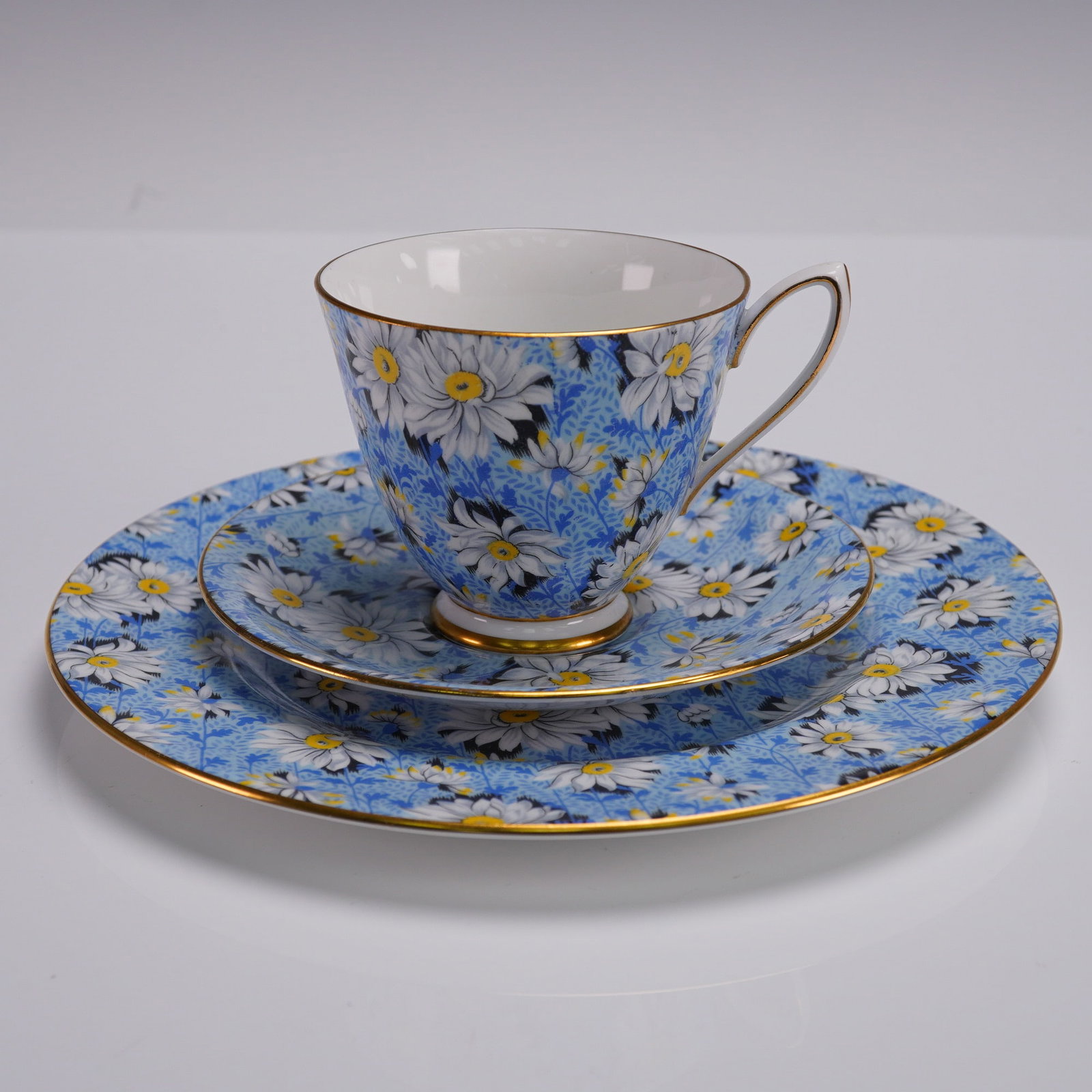 3pc Shelley Fine Bone China Teacup Set Daisy Chintz Pattern: Shelley England fine bone china 3-piece tea trio featuring an allover blue and white daisy chintz pattern with yellow centers, accented with gold trim. The set includes a tall flared teacup, a matchin