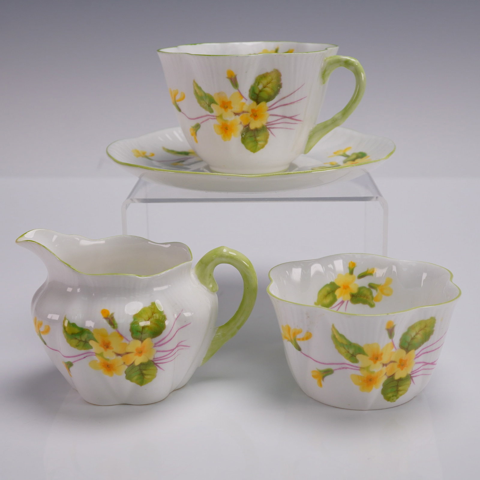 4pc Shelley Fine Bone China Tea Set Primrose Pattern: Shelley England fine bone china 4-piece tea set in the Primrose pattern, dating to the mid-20th century. This fluted set features a teacup with matching saucer, sugar bowl, and creamer, each decorated