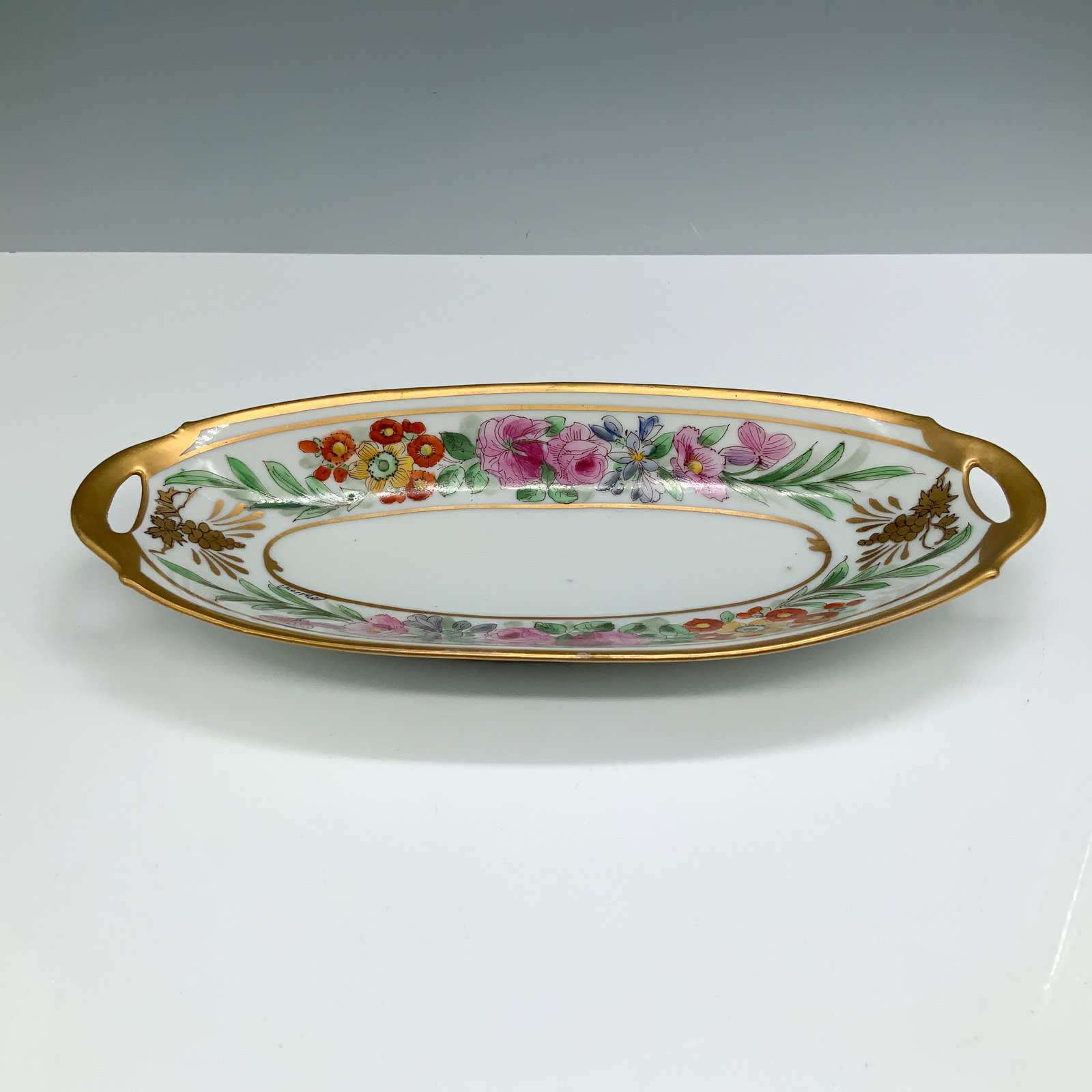 Pickard China Oval Floral Serving Dish: A beautifully crafted Pickard China oval serving dish featuring an intricate hand-painted floral design accented by vibrant colors and a delicate gilded trim. The edges are adorned with ornate open ha