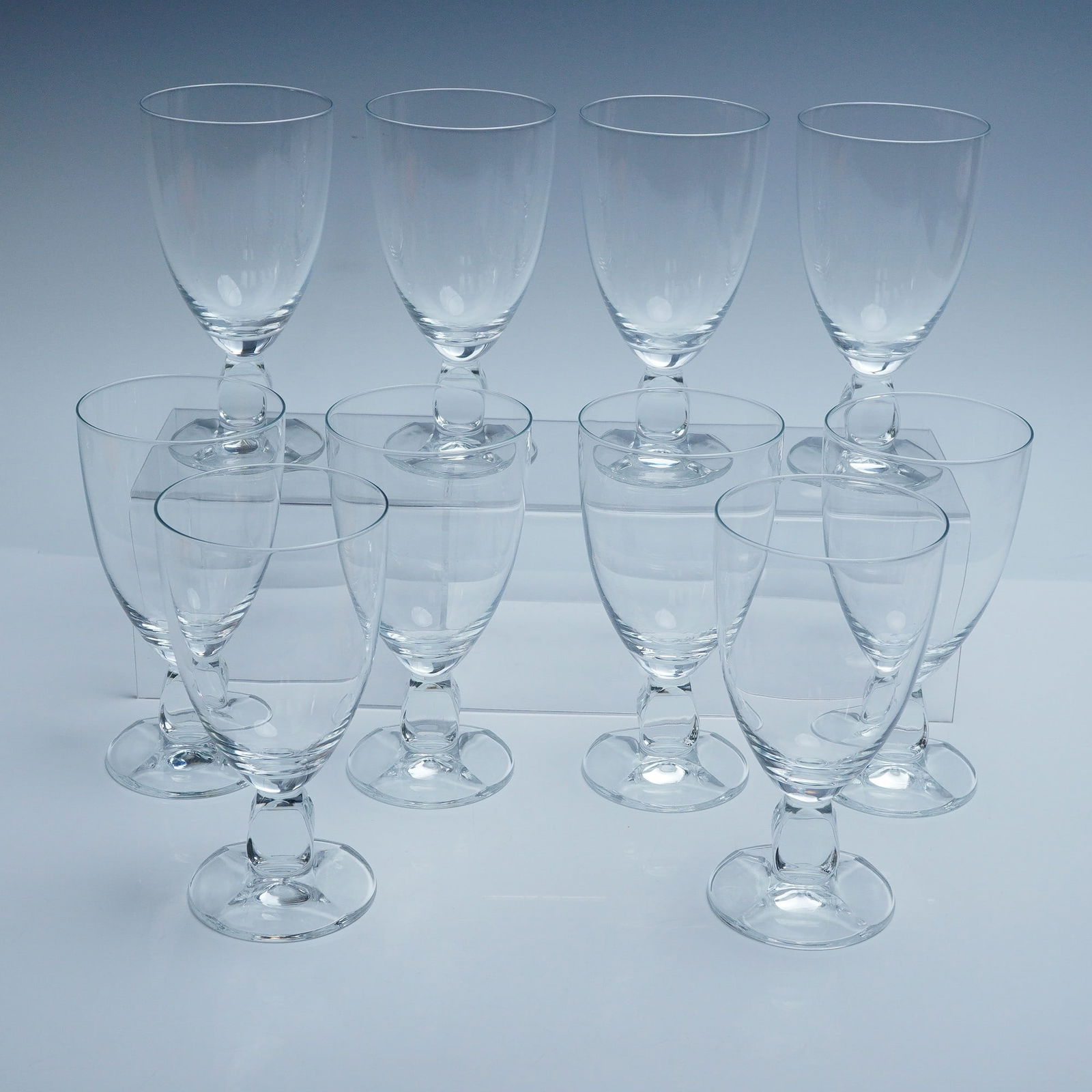 10pc Clear Crystal Goblets with Sculpted Stems: Set of 10 matching crystal goblets featuring a clean, rounded bowl and distinctive sculpted oval stem. The clear glass construction highlights their refined silhouette, ideal for serving water, wine,