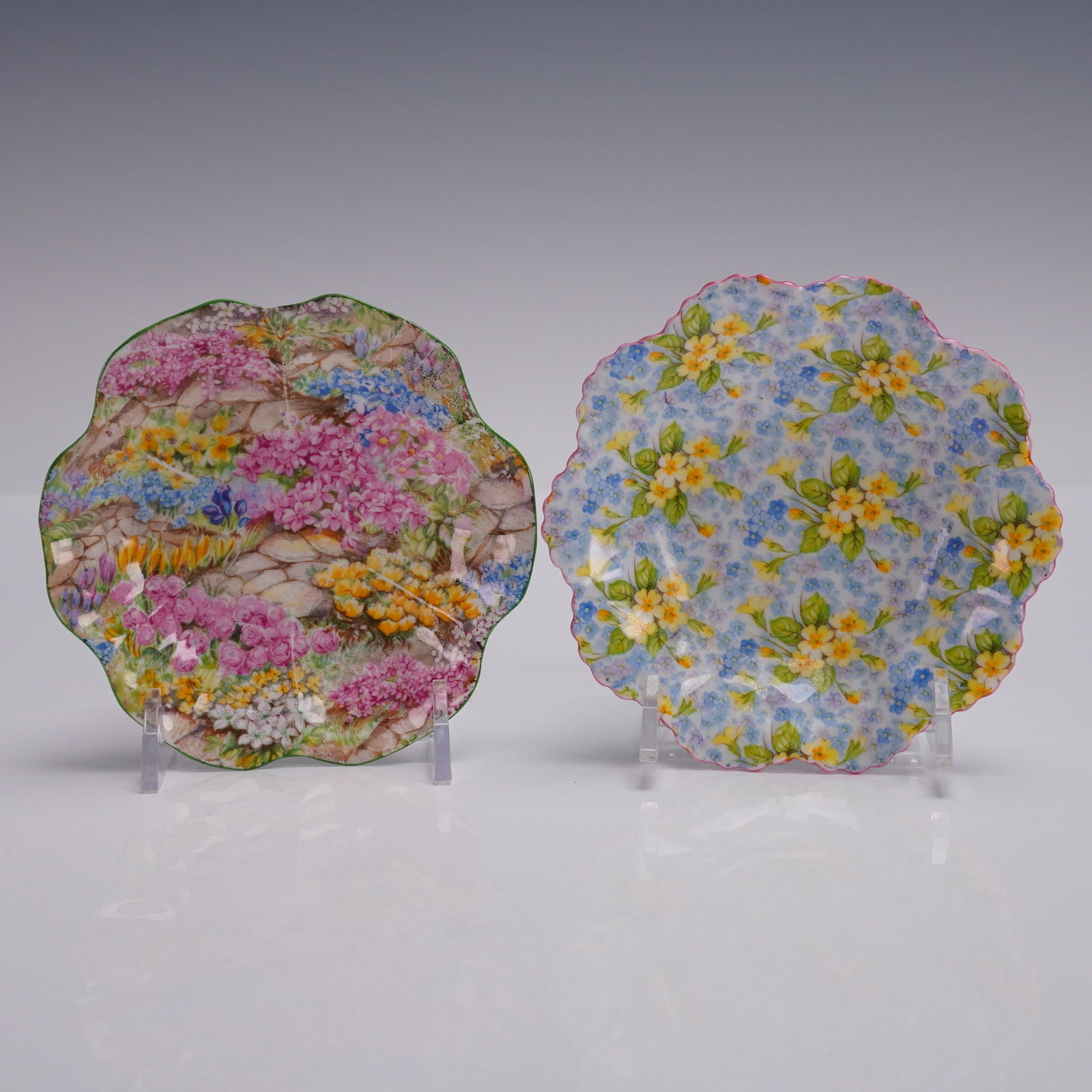 2pc Shelley Chintz Dishes, Rock Garden & Primrose Patterns: A pair of Shelley fine bone china chintz dishes with scalloped rims and full-coverage floral designs. One features the Rock Garden pattern with green trim, decorated in a profusion of colorful garden 