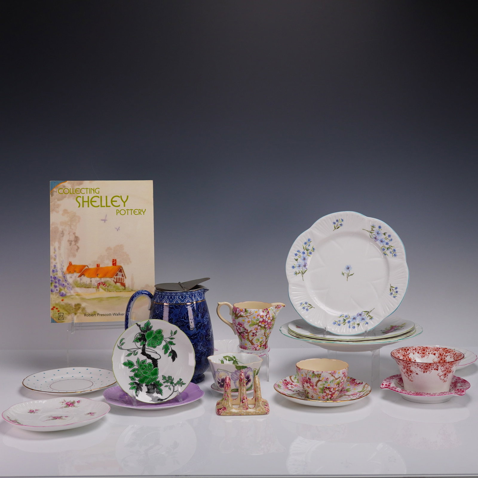 20pc Shelley England Teacups Saucers and China Book Lot: Twenty-piece collection of Shelley England fine bone china and reference material. Includes a variety of vintage teacups, saucers, side plates, and creamers in several well-known Shelley patterns such