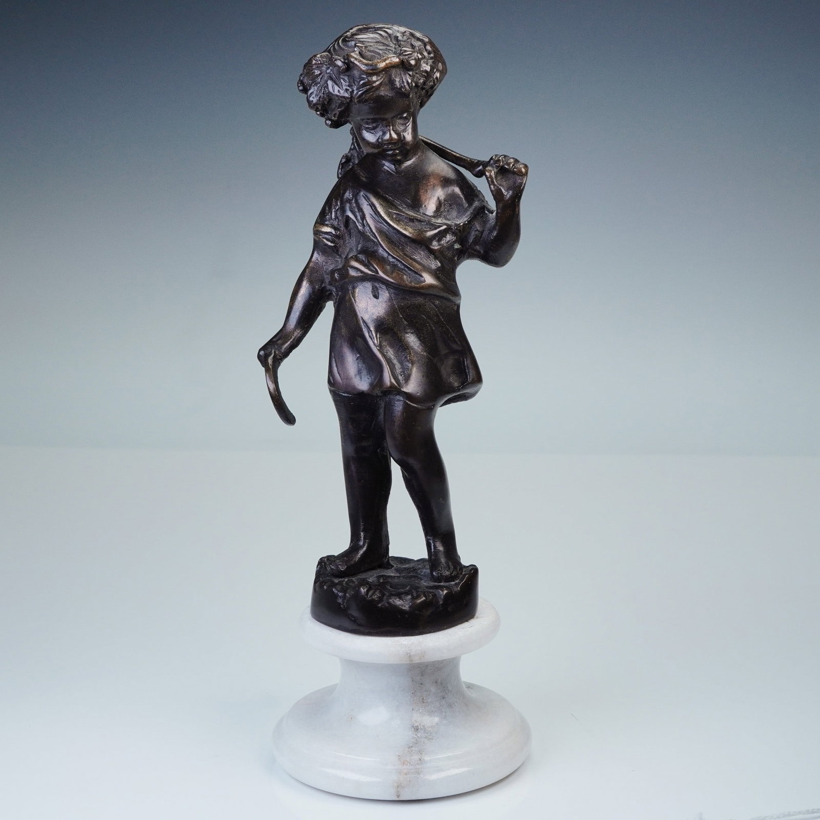 Continental Bronze Figure of a Boy with Grapes: Unsigned bronze figure of a young boy walking with a curved branch over his shoulders, from which hangs a bunch of grapes. Nicely modeled with textured hair and garments. Finished in a dark brown pati