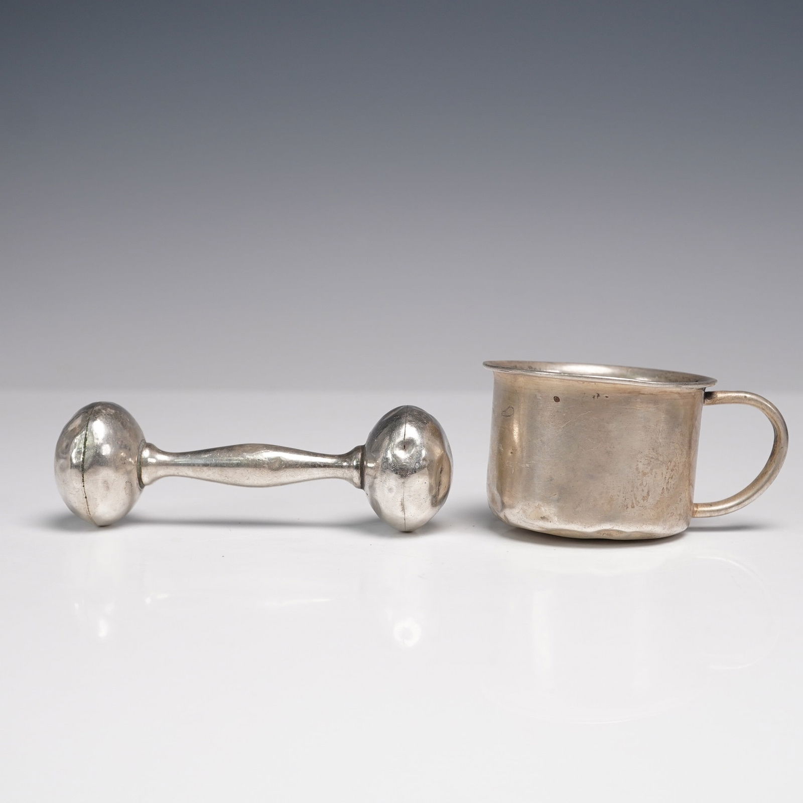 2pc Sterling Silver Baby Rattle and Cup, Marked IONA and WEB: Sterling silver baby rattle and cup, early to mid-20th century. The rattle features a classic dumbbell form and is marked "STERLING WEB." The small handled cup is marked "IONA STERLING 1027." Both pie