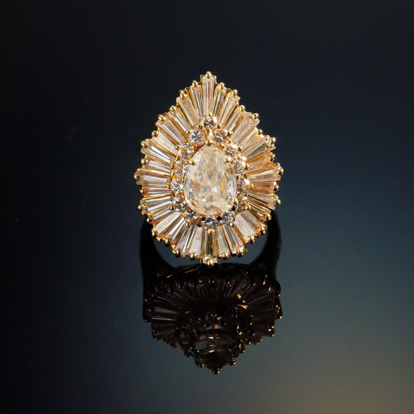 18k Yellow Gold and 5.5 Carat Cocktail Diamond Ring: A masterclass in dramatic elegance, this lavish cocktail ring is fashioned in glowing 18k yellow gold and features a striking old cut, 1.5 carat diamond at its center. The principal diamond is encircl
