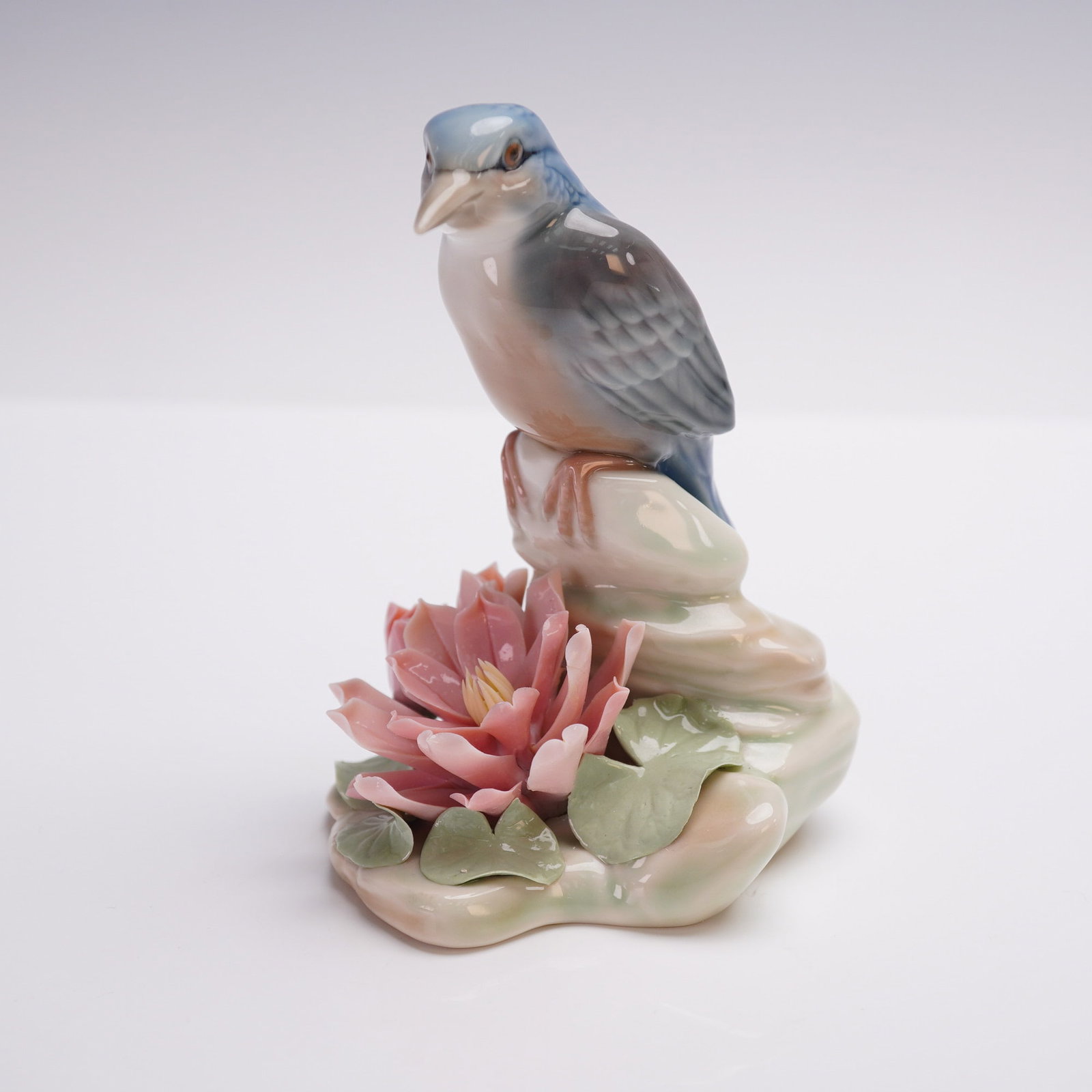 Lladro Porcelain Figurine, Little Bird 1001301: Lladro porcelain figurine titled Little Bird, model 1001301, featuring a delicately sculpted blue and gray bird perched on a pale green rock beside a blooming pink lotus flower with lily pads. Designe