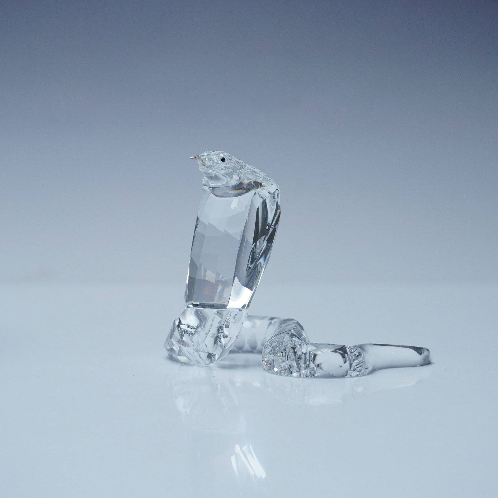 Swarovski Silver Crystal Figurine, Cobra Snake: This Swarovski Silver Crystal Cobra Snake figurine is intricately crafted with clear precision-cut crystal, capturing the cobra in a striking pose with its hood flared and body coiled. The detailed fe