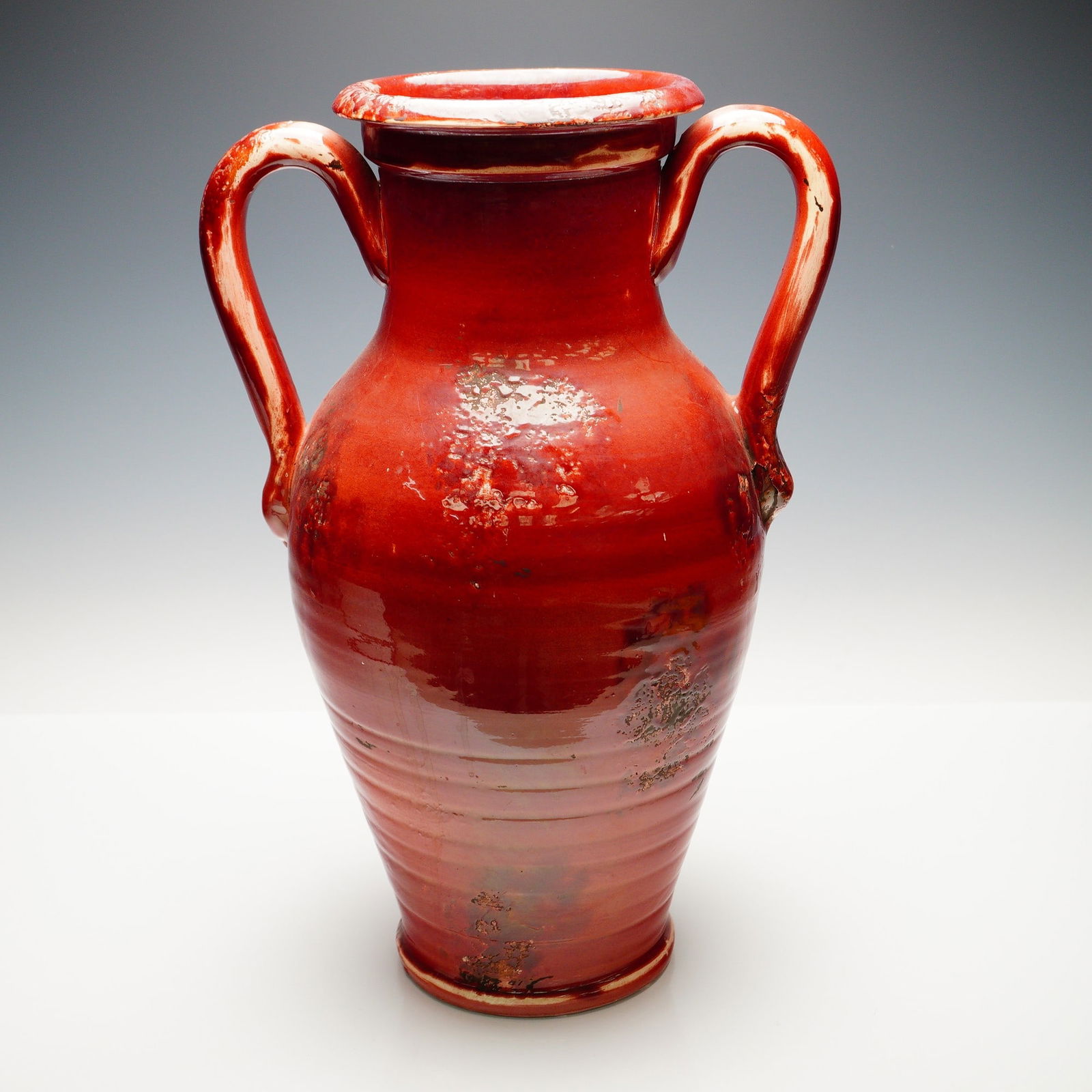 Italian Red Glazed Pottery Amphora Vase: Large Tuscan pottery amphora vase with a rich, high-gloss red glaze, accented by scattered metallic inclusions and natural glaze pitting. The hand-thrown form features a pronounced ringed neck with sq