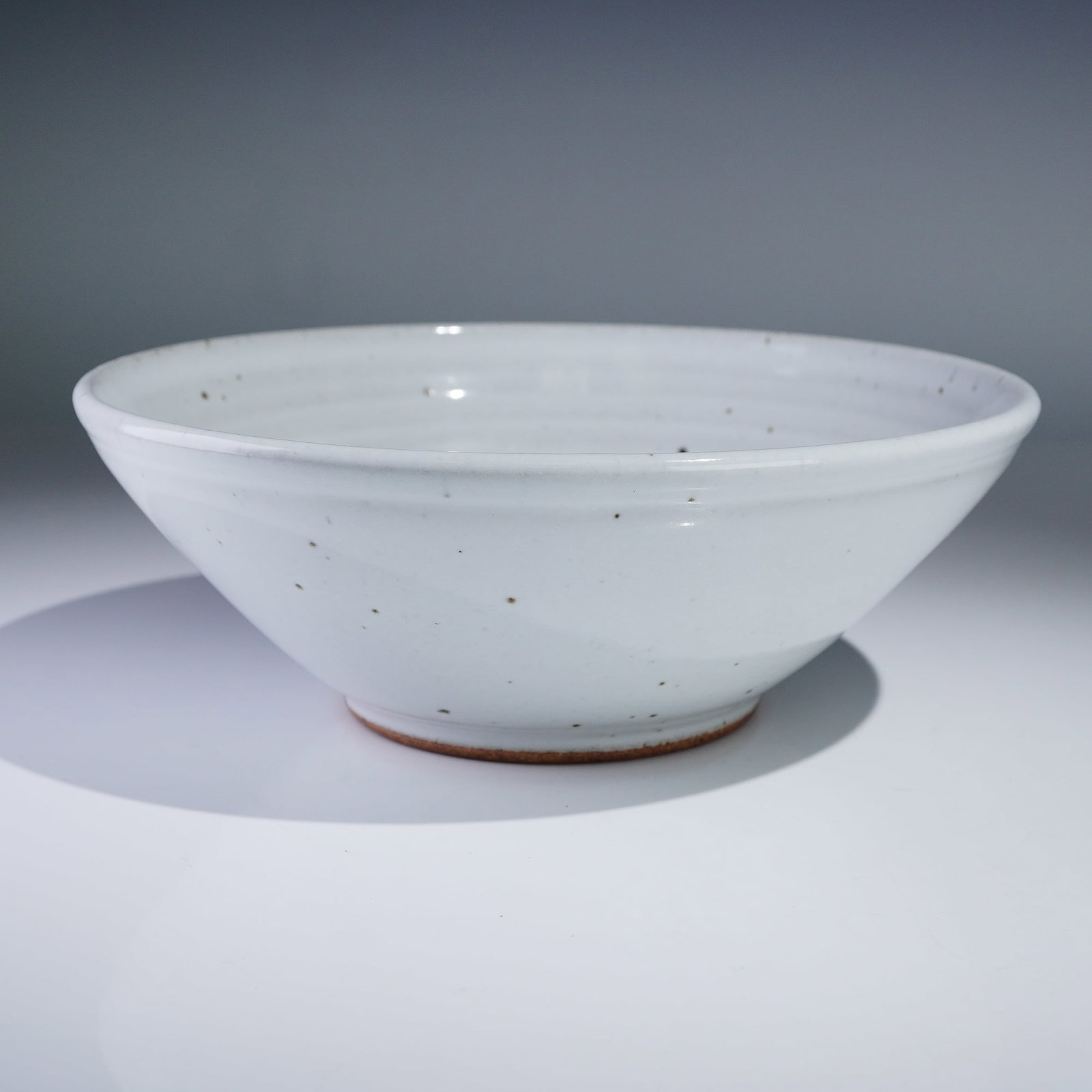 Maine Kiln Works Pottery Bowl Blue Brush Design: Hand-thrown stoneware bowl by Maine Kiln Works of Gouldsboro, Maine, featuring a speckled white glaze with cobalt blue brushstroke design on the interior. The underside is fully marked with the studio
