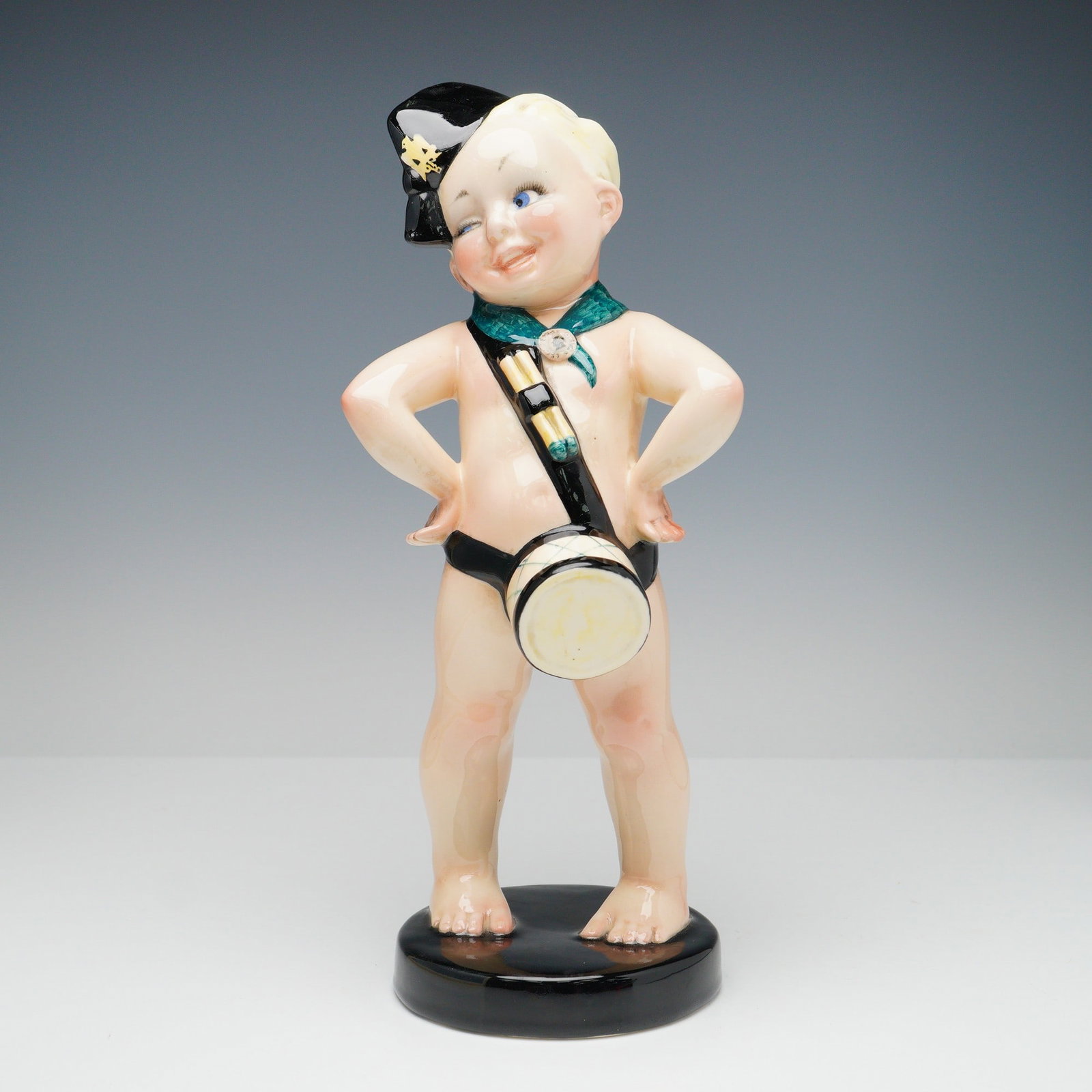 Essevi by Sandro Vacchetti Figurine, Balillino: Polychrome ceramic figurine by Sandro Vacchetti for Essevi, depicting a nude young boy standing confidently with hands on hips. The child wears a black cap with pal-yellow detail, a green neckerchief,