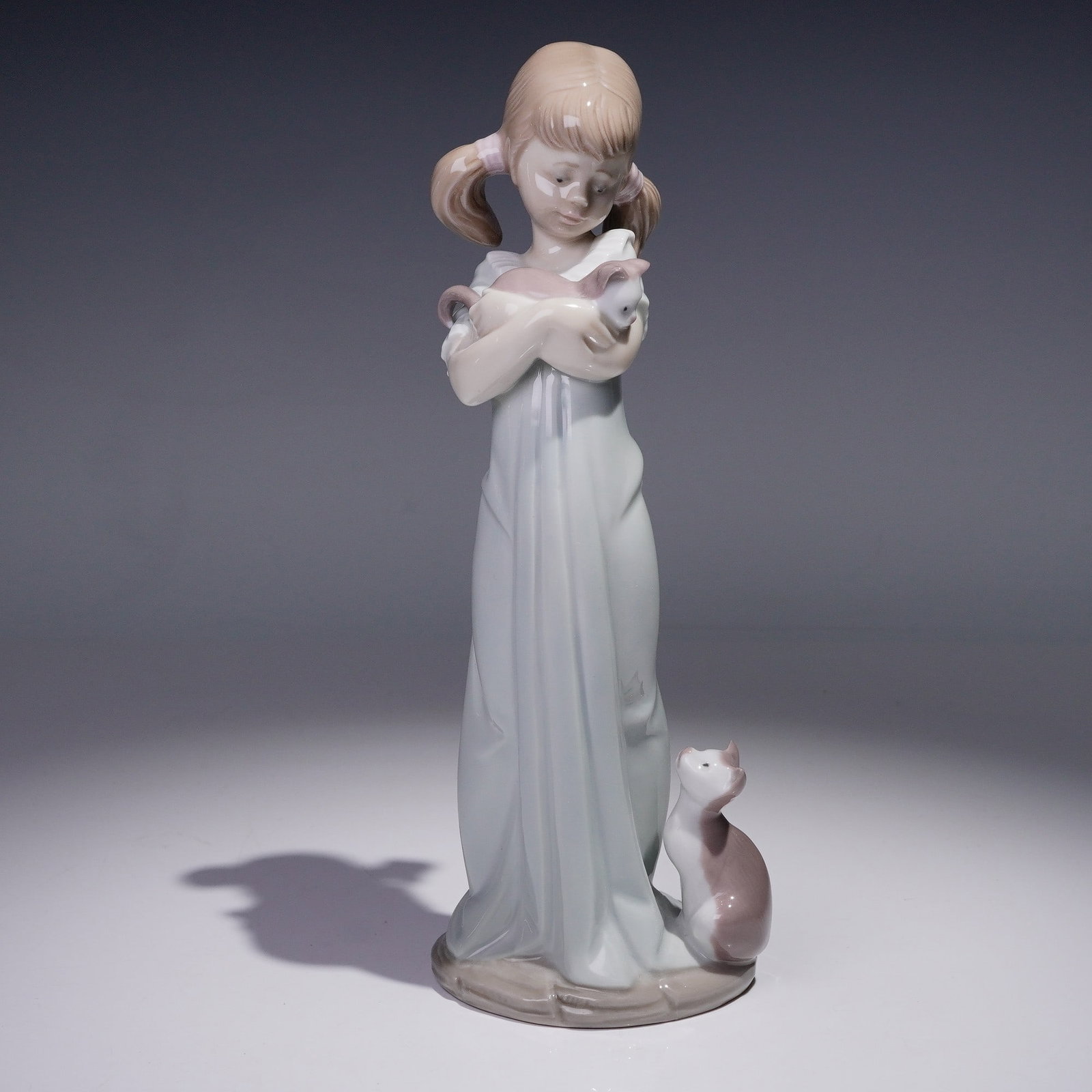 Lladro Porcelain Figurine, Don't Forget Me! 1005743: Glossy finish porcelain depicting a young girl in a long gown gently cradling a white dove in her arms while a curious cat looks up from her feet, capturing the innocence and wonder of childhood. Llad