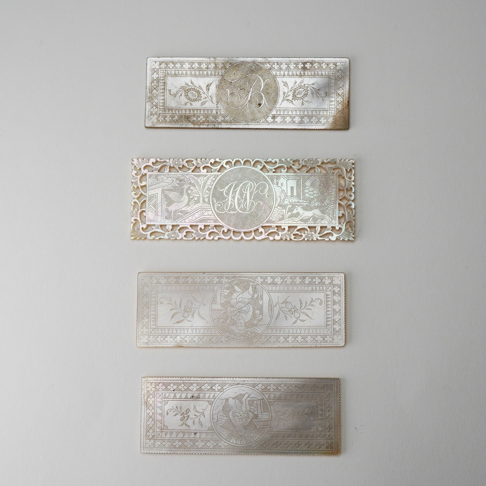 4pc Chinese Rectangular Mother of Pearl Figural Gaming Chips: Group of four finely engraved 19th-century Chinese export gaming chips in rectangular mother of pearl form, featuring a variety of detailed motifs. The lot includes chips with central monograms framed