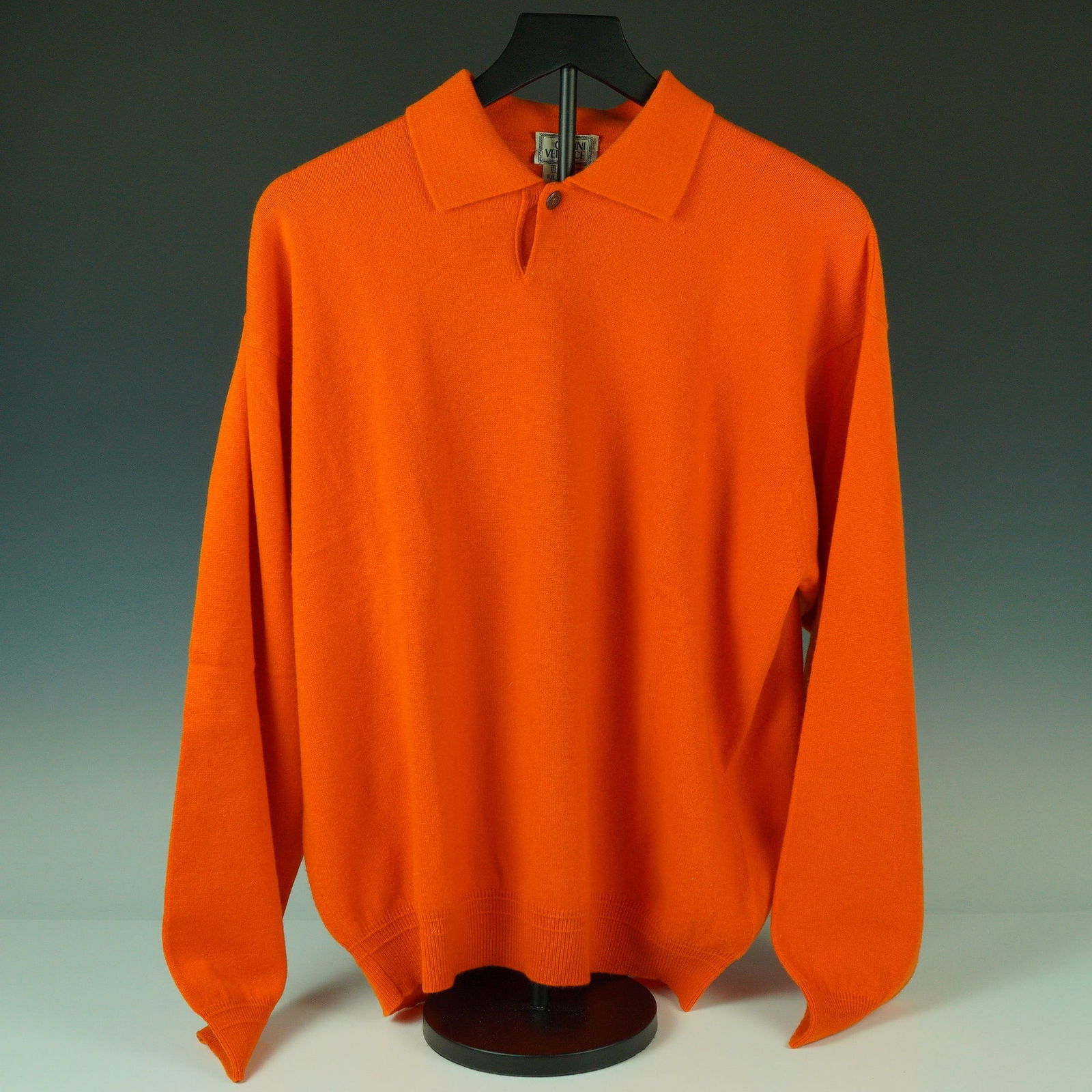 Gianni Versace Orange Cashmere Polo Collar Sweater: Bold, sculptural, and unmistakably Versace, this standout cashmere sweater comes in a striking shade of vivid orange. Designed with a classic polo collar and single-button placket, the look is elevate