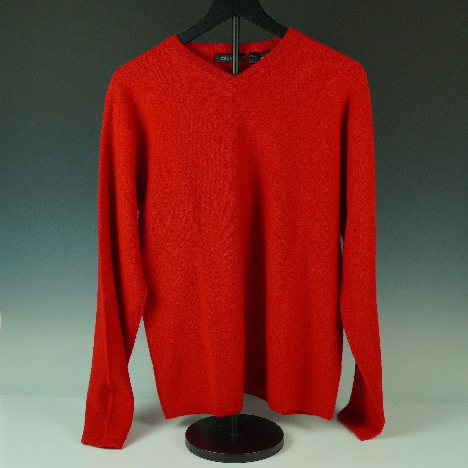 DKNY Red Cashmere V-Neck Sweater: Offered here is a vivid red V-neck sweater by DKNY, finely knit in 100% cashmere for a soft and lightweight feel. Designed with ribbed trim along the neckline, cuffs, and hem, this versatile piece sho