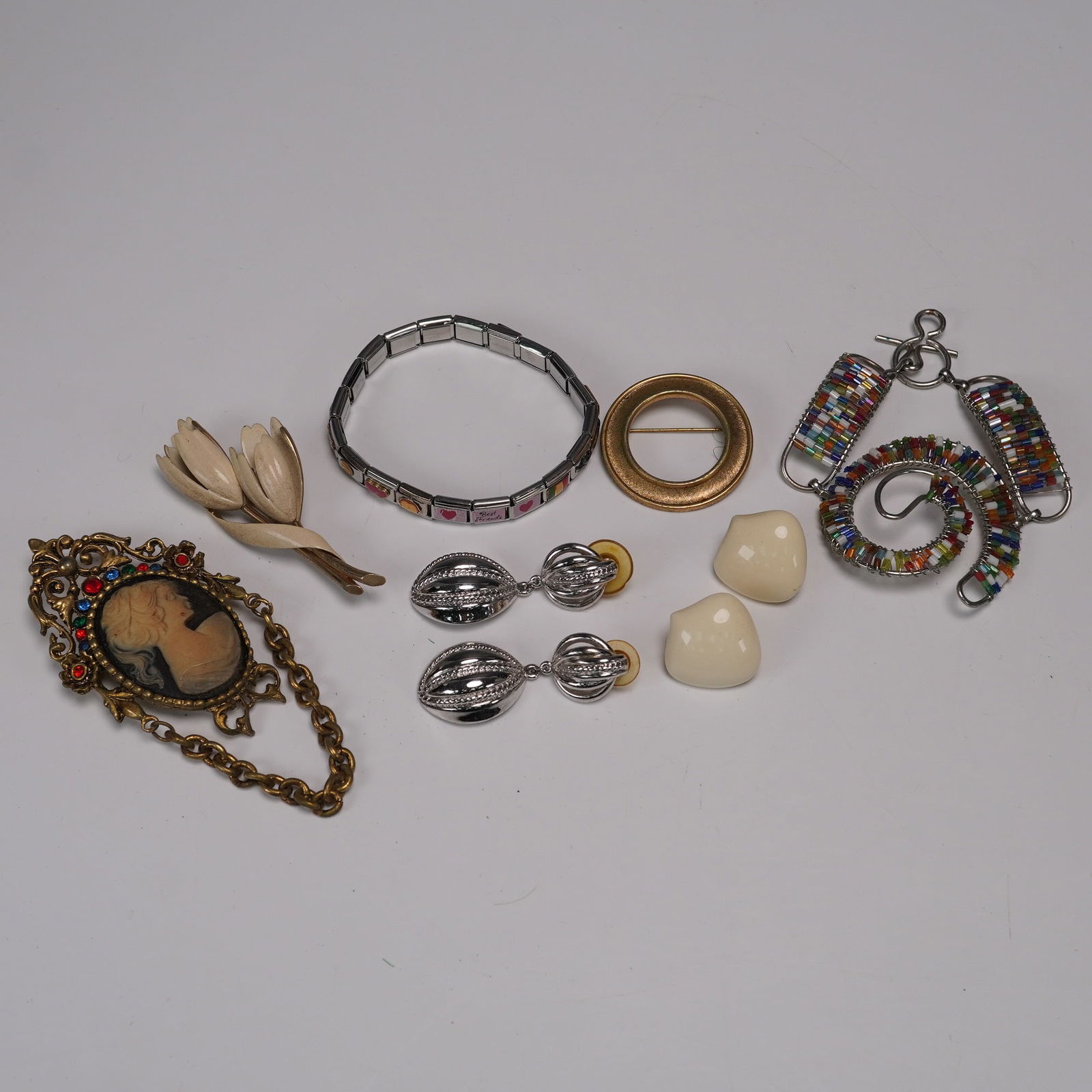 9pc Vintage Jewelry Assortment - Trifari, Monet & More: This lot features a delightful mix of nine vintage costume jewelry pieces. Included are three brooches: a gold-tone circular pin signed Trifari with a subtle brushed texture, a Monet-signed cream enam