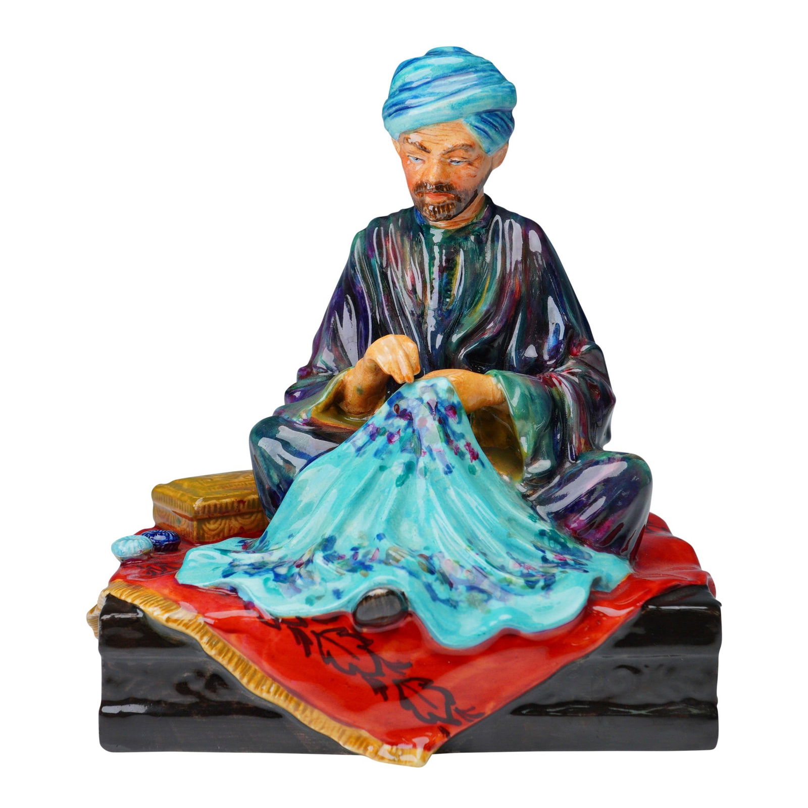 Studio Potter Figurine, Embroiderer of Kashmir: A finely modeled and vividly hand-painted ceramic figurine titled Embroiderer of Kashmir from the Studio Pottery line, sculpted by Reg Johnson. The figure depicts a seated man in traditional attire, e