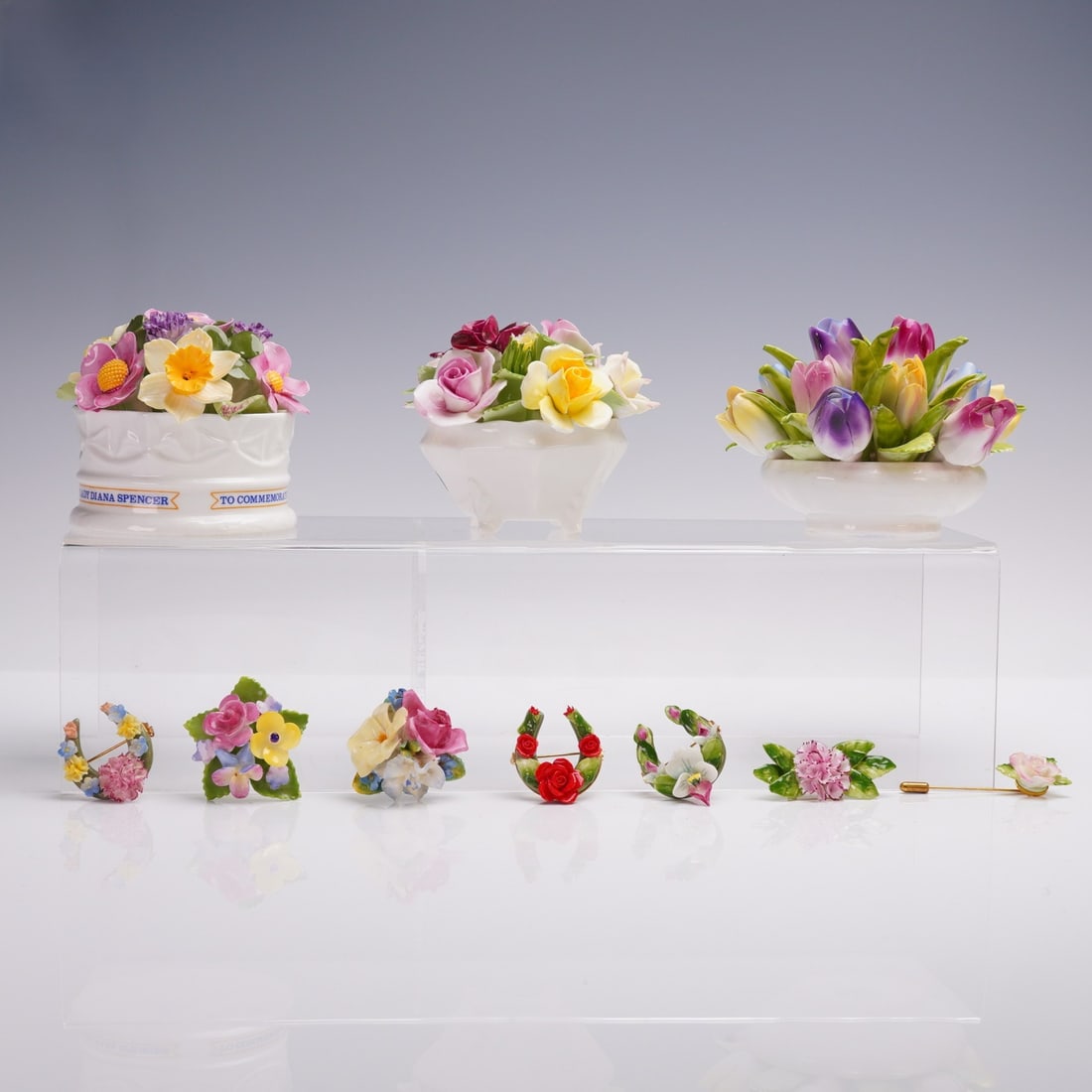 10pc Royal Doulton Aynsley Staffordshire Floral Pins Group: 10pc grouping includes 7 porcelain floral brooch pins and 3 miniature porcelain flower arrangements. Makers include Royal Doulton, Aynsley, Staffordshire, and Aristocrat, with clear backstamps on most