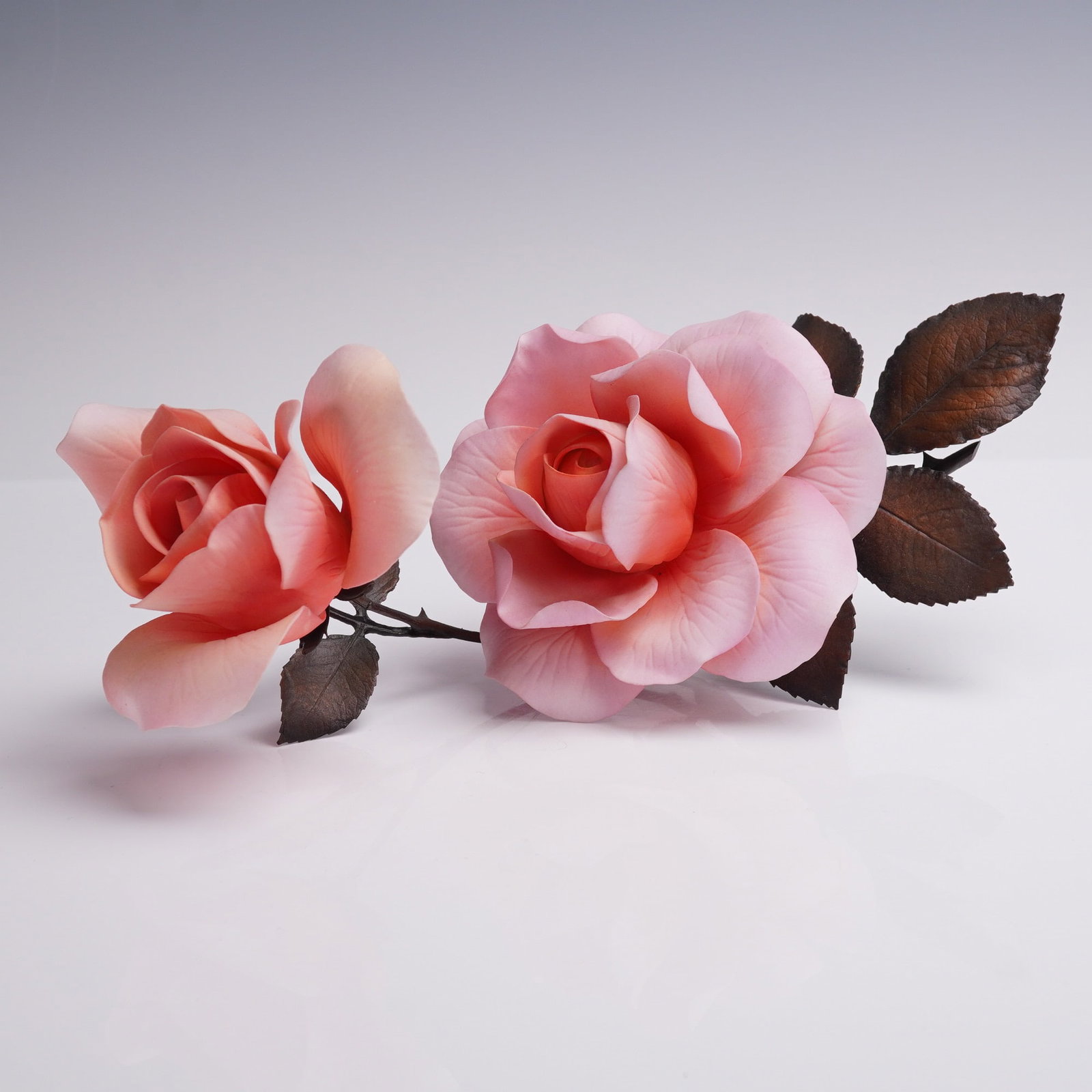 Boehm Flower Sculpture, Queen Elizabeth Rose 60123: A Boehm bone china floral sculpture titled Queen Elizabeth Rose, model 60123. This limited issue piece features two full pink roses in delicate bloom, accented by textured bronze-toned metal leaves an