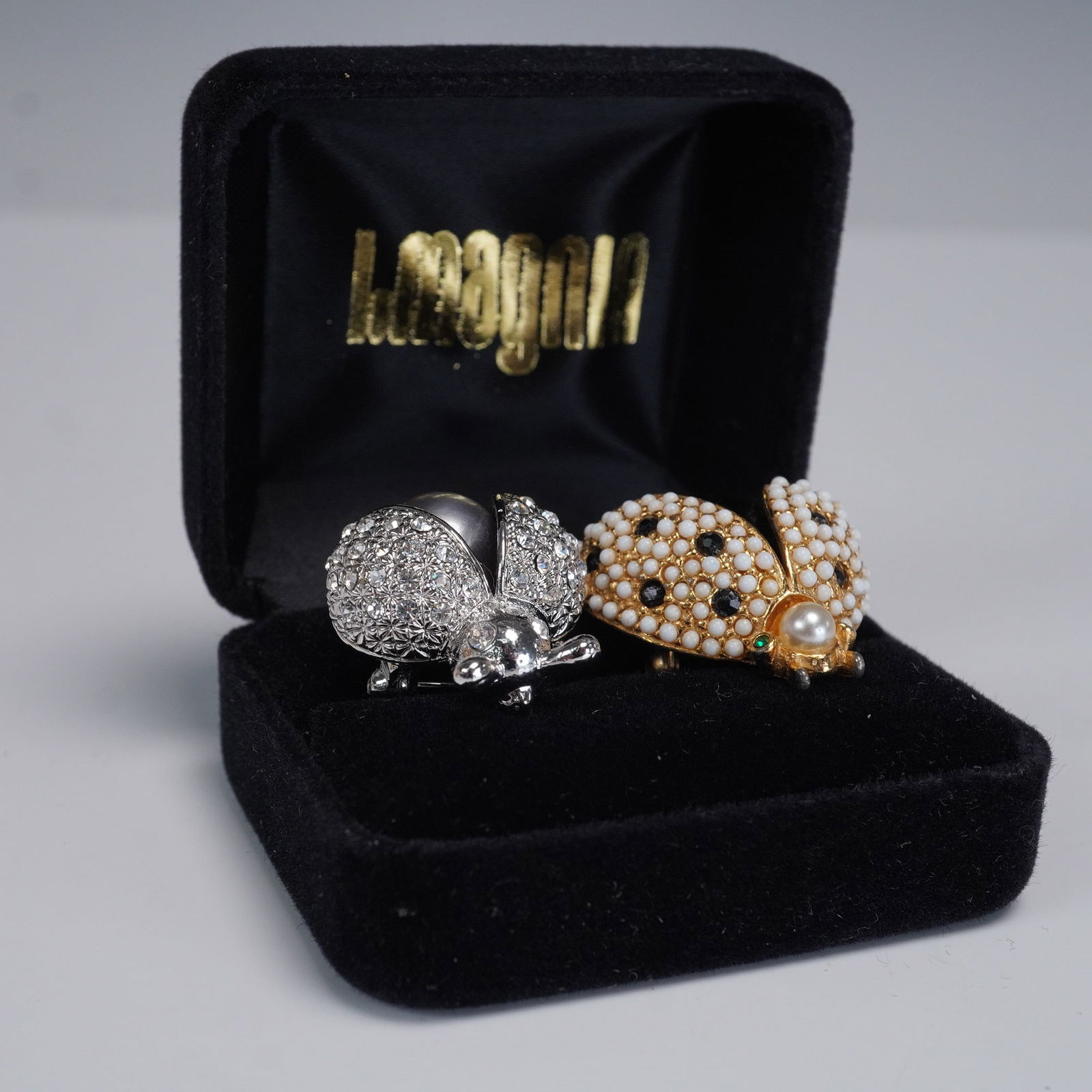 Pair of Figural Ladybug Brooches, Hattie Carnegie and Rhinestone Pave: A captivating pair of vintage figural ladybug brooches, brimming with mid-century charm and collector appeal. The first brooch is a signed Hattie Carnegie design, lavishly enameled and embellished wit