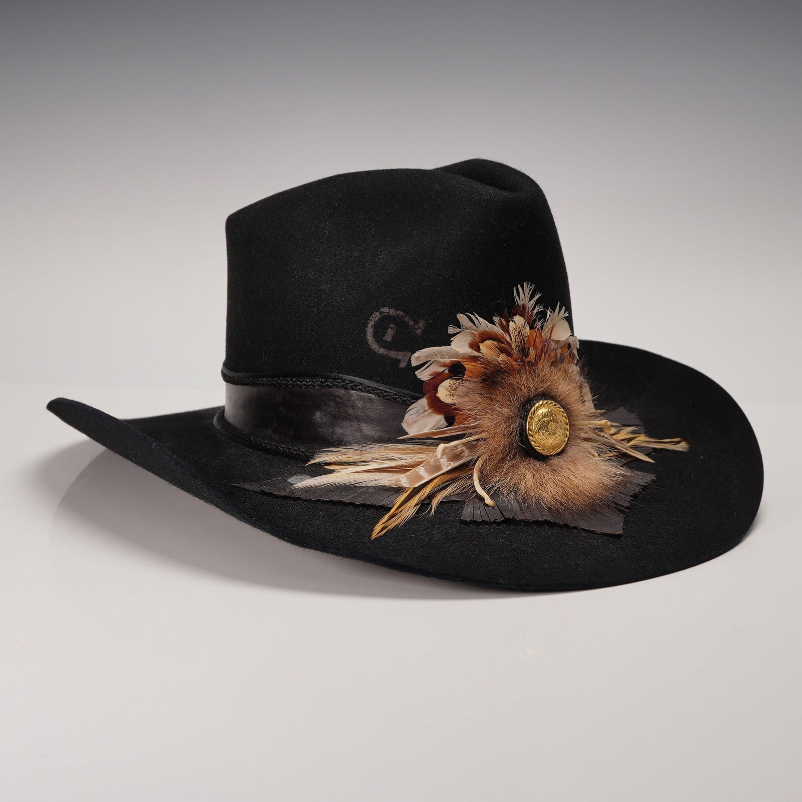 Charlie 1 Horse Cowboy Hat Feather Trim with Original Box: Black western-style cowboy hat by Charlie 1 Horse Hat Co., featuring the brand's distinctive horseshoe-C logo on the crown and a dramatic side spray of feathers, fur, and button trim. The satin-lined