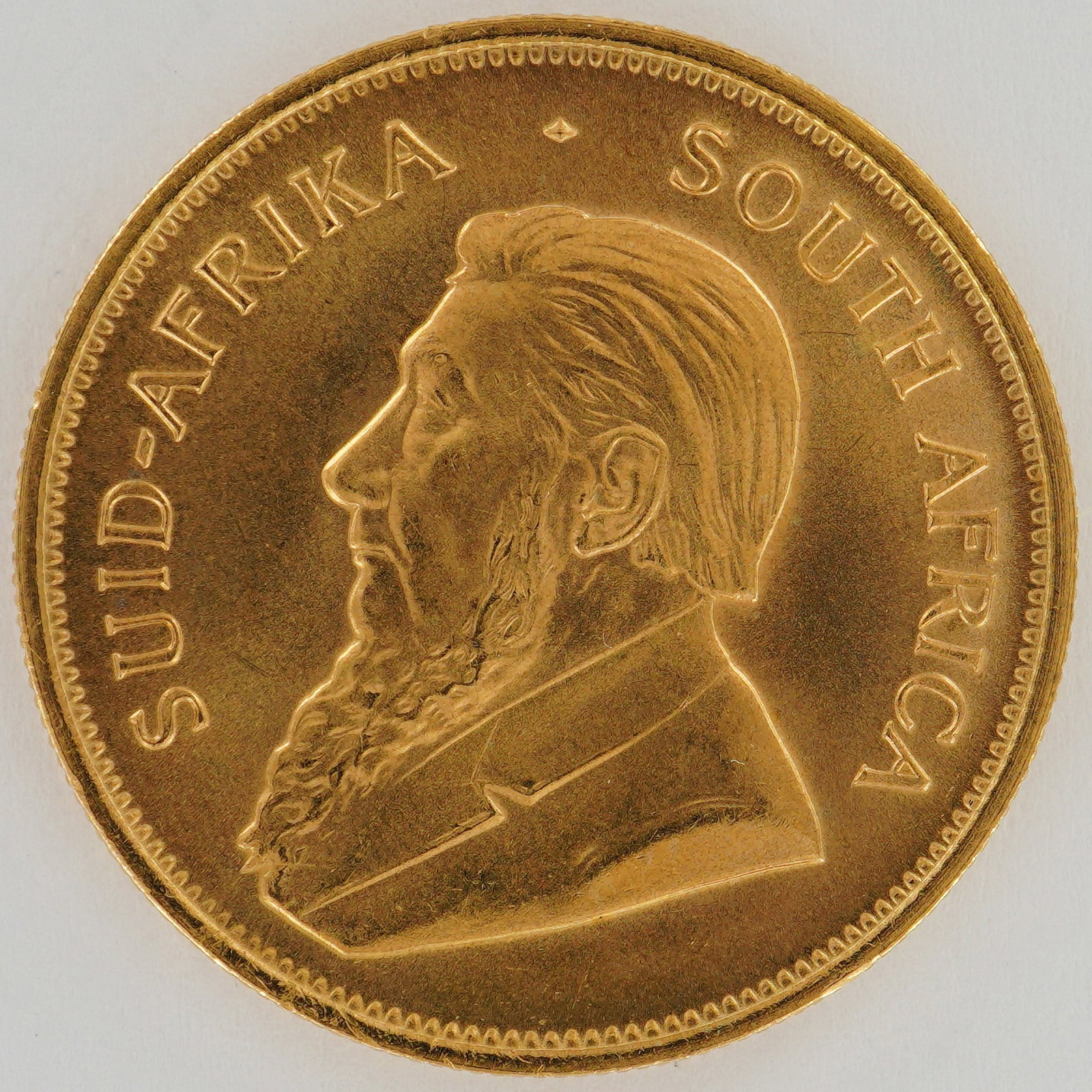 1984 South African 1 oz Gold Krugerrand Coin: This South African gold bullion coin, issued in 1984, is composed of one troy ounce of fine gold. The obverse features a left-facing portrait of Paul Kruger, former President of the South African Repu