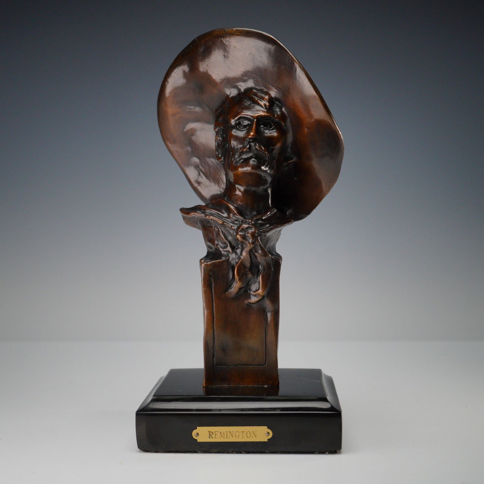 After Frederic Remington, The Sergeant Bronze Bust: A patinated bronze bust depicting a rugged Western figure, modeled after "The Sergeant" by Frederic Remington (American, 1861-1909). The sculpture features a prominent wide-brimmed hat, thick mustache