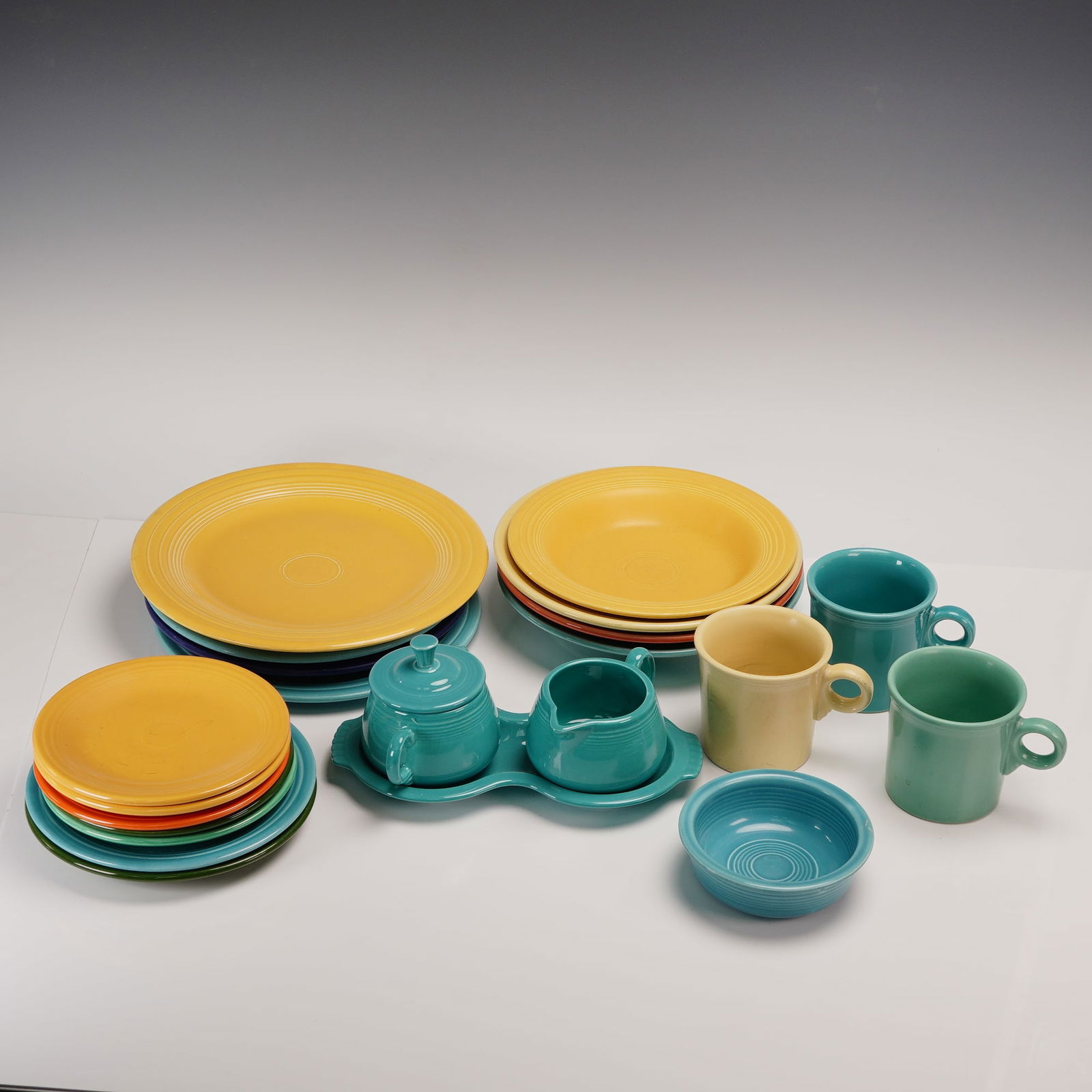 23pc Fiesta Dinnerware Set in Assorted Colors: Colorful and iconic Fiesta dinnerware set comprising 4 dinner plates, 5 bread and butter plates, 2 salad plates, 4 soup bowls, 1 small bowl, 3 cups, 1 creamer, 1 lidded sugar, and 1 undertray. Glazed