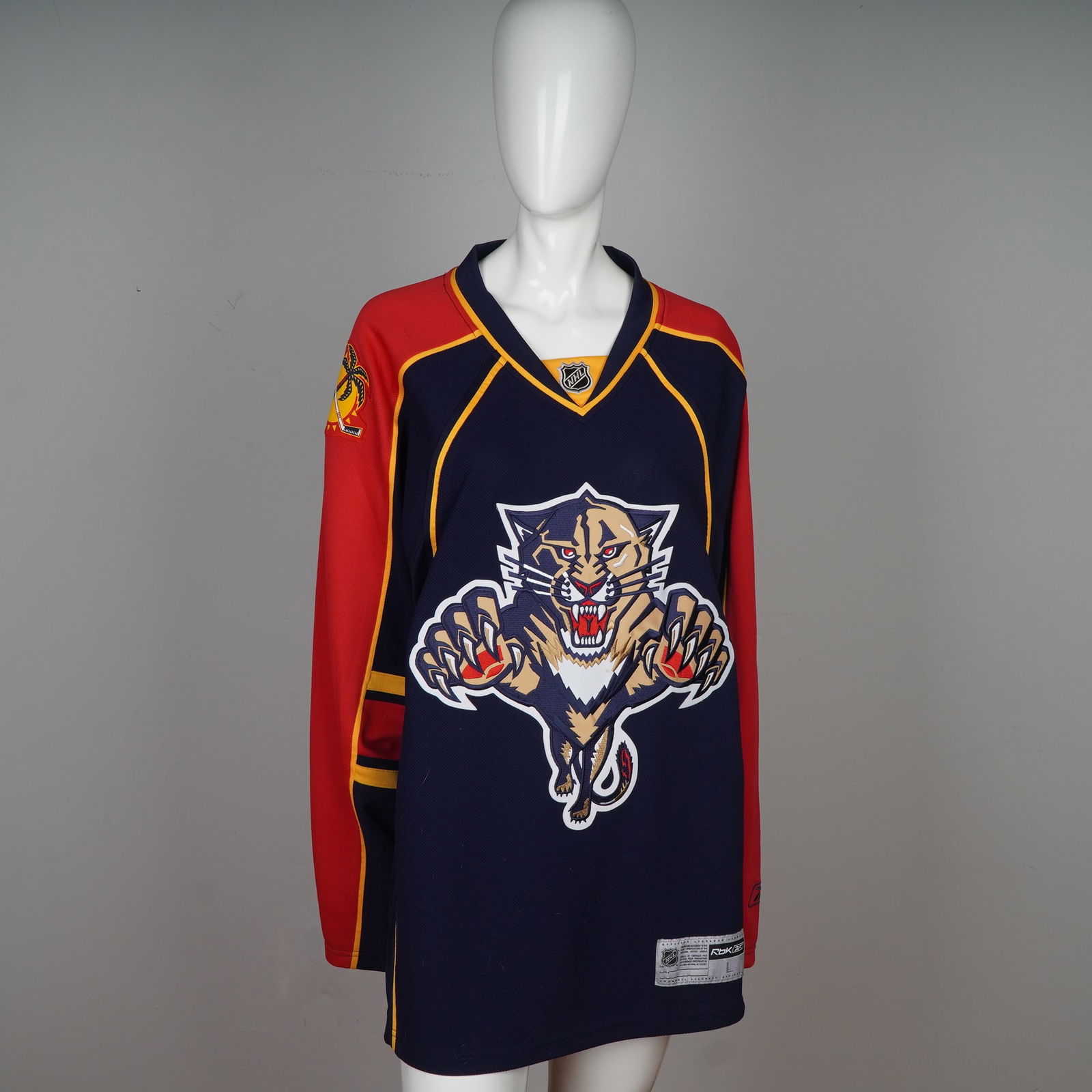 Reebok Florida Panthers NHL Hockey Jersey: Presented is an officially licensed Florida Panthers NHL hockey jersey by Reebok, size large (L/G). This dynamic jersey features the iconic leaping panther logo across the chest, with contrasting red