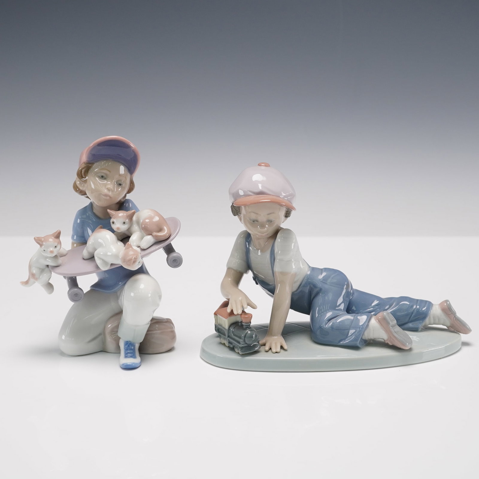 2pc Lladro Porcelain Figurines Little Riders and All Aboard: Pair of Lladro porcelain figurines including Little Riders, item number 01007623, sculpted by Salvador Debon, and All Aboard, item number 01007619. Little Riders features a girl kneeling with a skateb