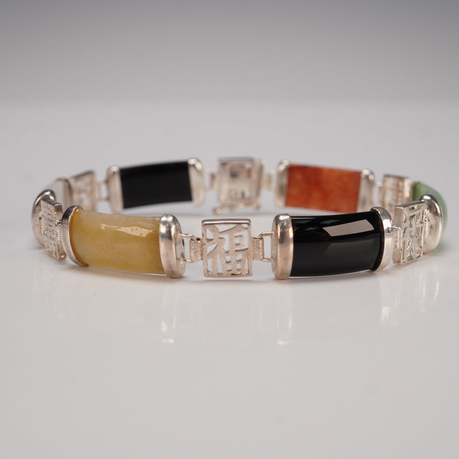 925 Sterling Multi-Color Jade Link Bracelet Chinese Inspired: This beautiful bracelet features alternating multi-colored stones, possibly including jade, serpentine, aventurine, or dyed agate, each separated by intricate silver links. The stones come in hues of 