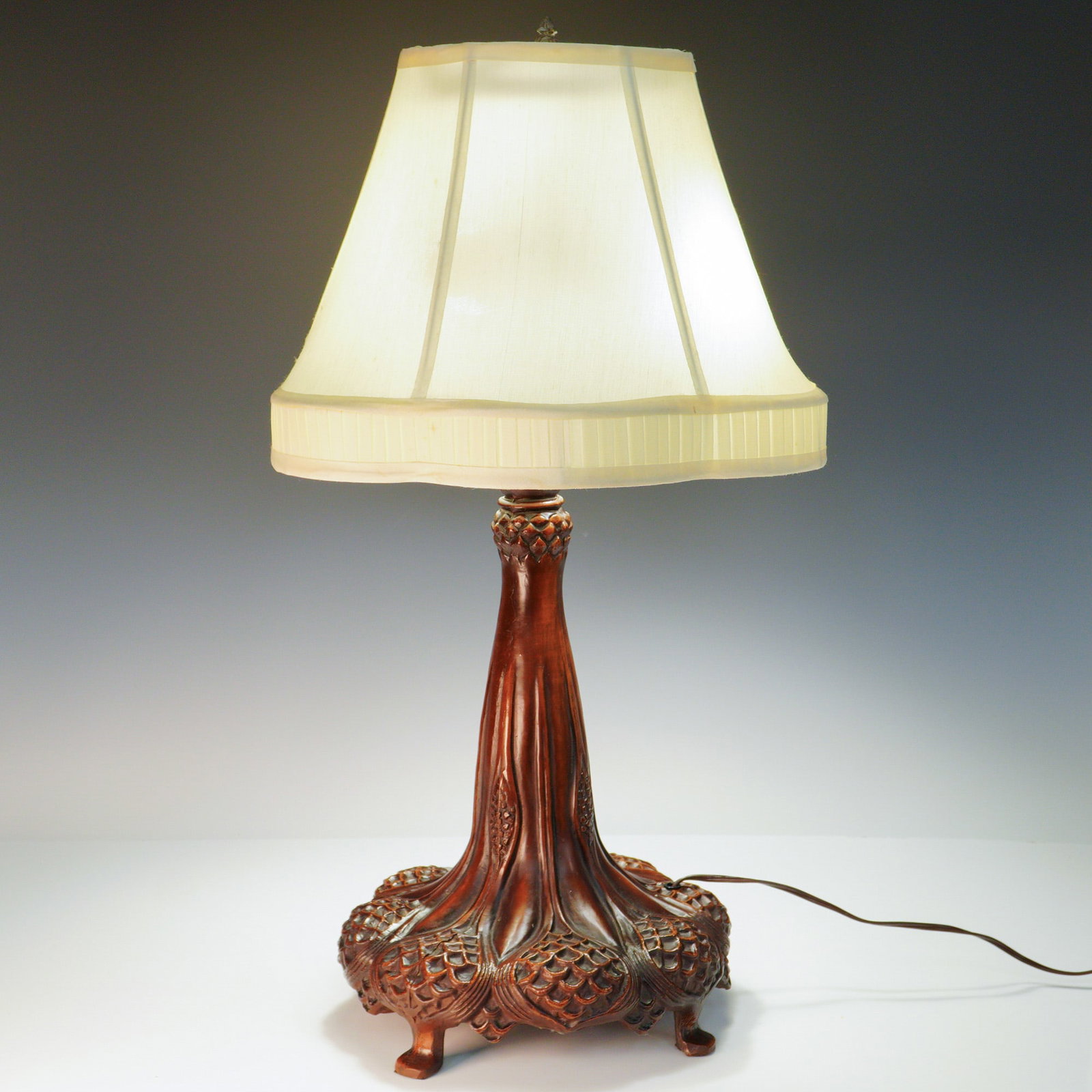 Tiffany Style Art Nouveau Lamp with Faux-Carved Metal Base: An Art Nouveau-inspired table lamp in the Tiffany style, with a molded metal base convincingly cast and finished to emulate finely carved wood. Decorative botanical reliefs and an organic, flowing sil
