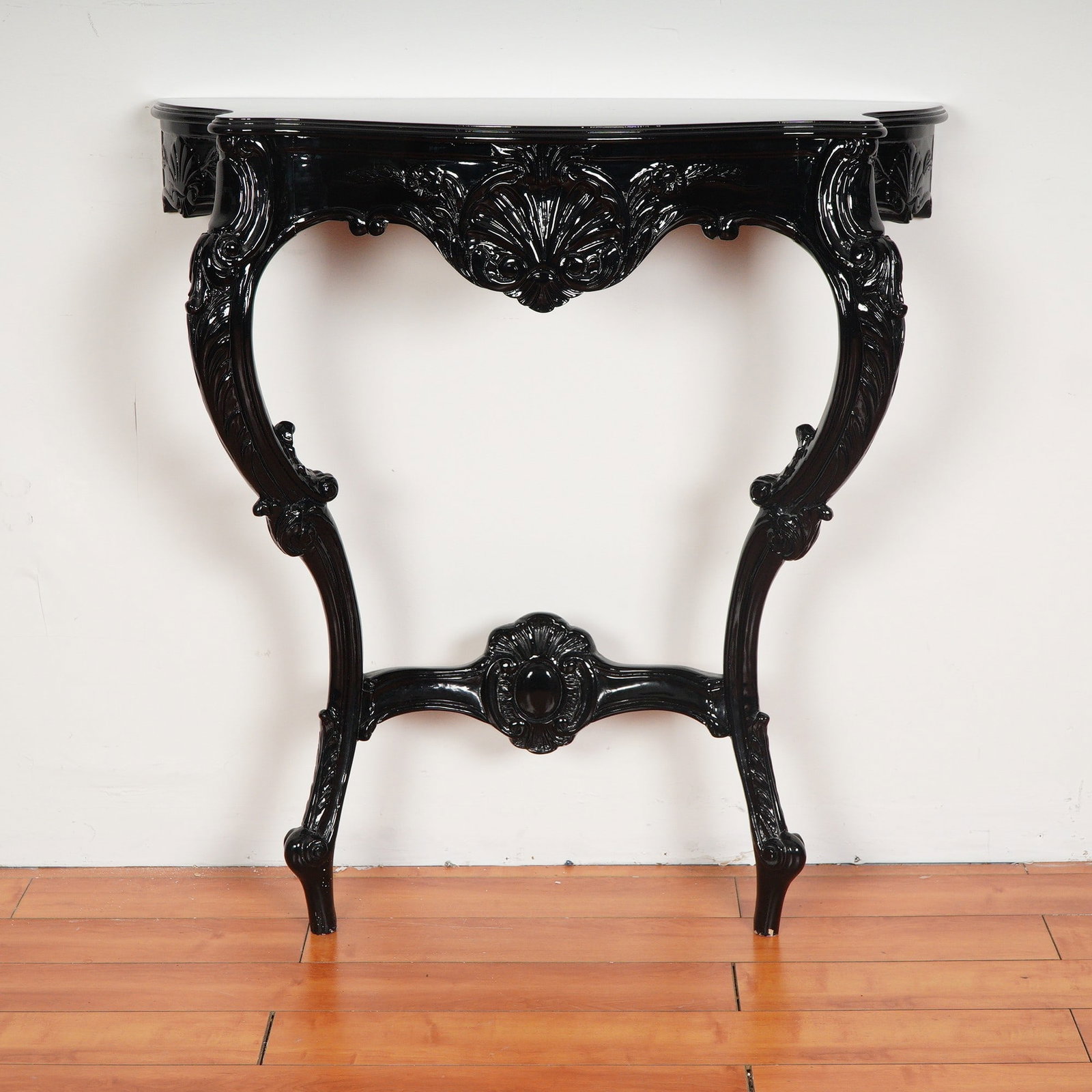 Black Lacquer Finish Rococo Revival Wall Console Table: Elegant Rococo Revival console table finished in a high-gloss black lacquer paint, showcasing an ornately carved apron with central scallop shell motif, scrolling acanthus leaves, and floral accents. 