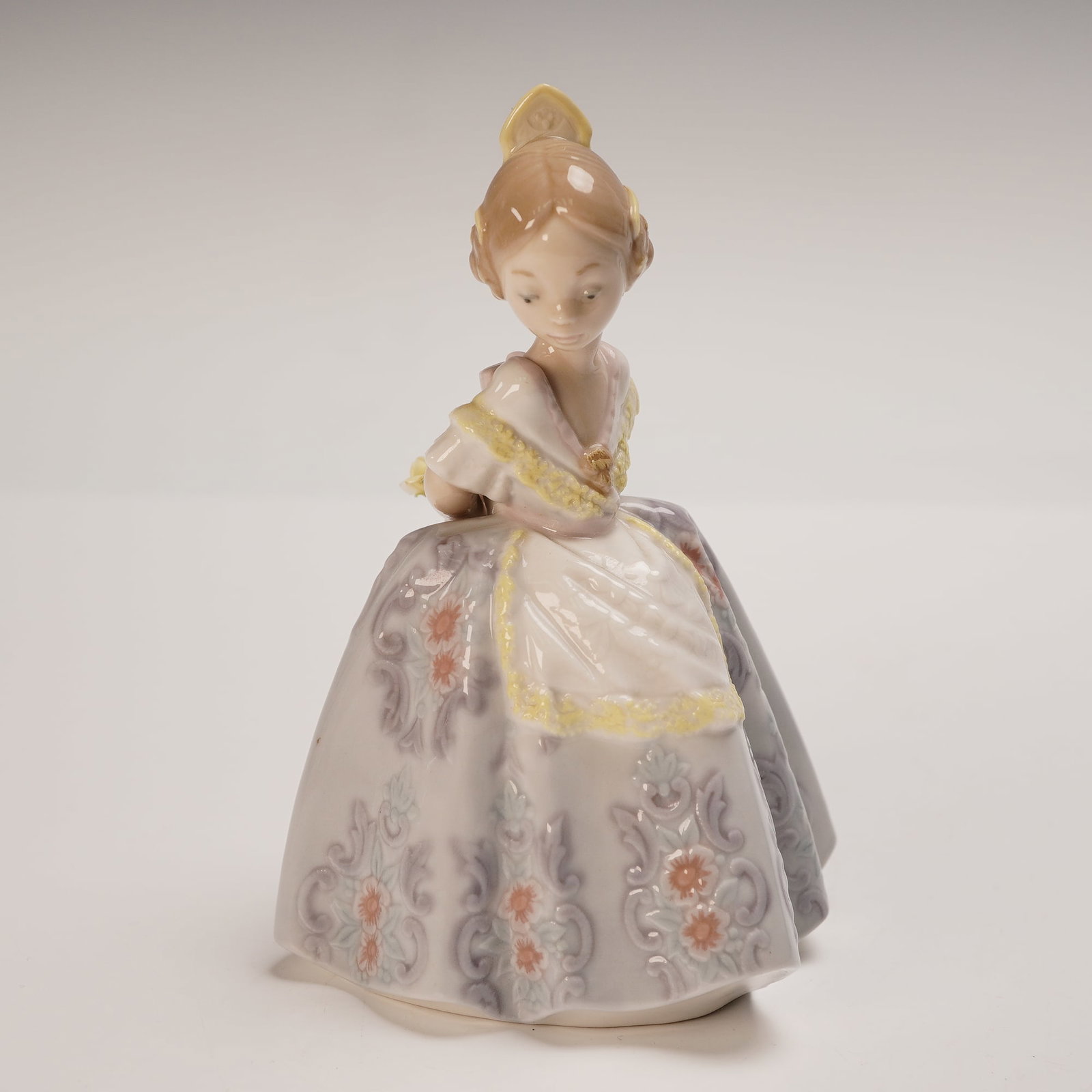 Lladro Porcelain Figurine, Pepita 1005374: Introduced in 1986, this exquisite Lladro porcelain figurine by sculptor Salvador Debon captures the poised elegance of a young girl in a traditional gown. Her lavender skirt is adorned with intricate