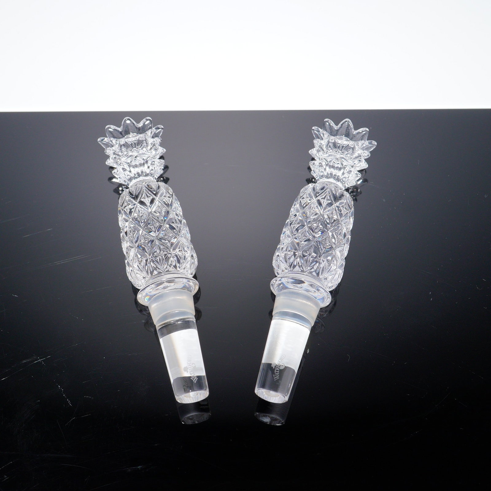 2pc Waterford Crystal Pineapple Bottle Stoppers with Boxes: A refined 2-piece set of Waterford Crystal pineapple bottle stoppers, each with a diamond-cut body and sculpted crown finial. Both retain their original boxes and feature the etched Waterford acid mar