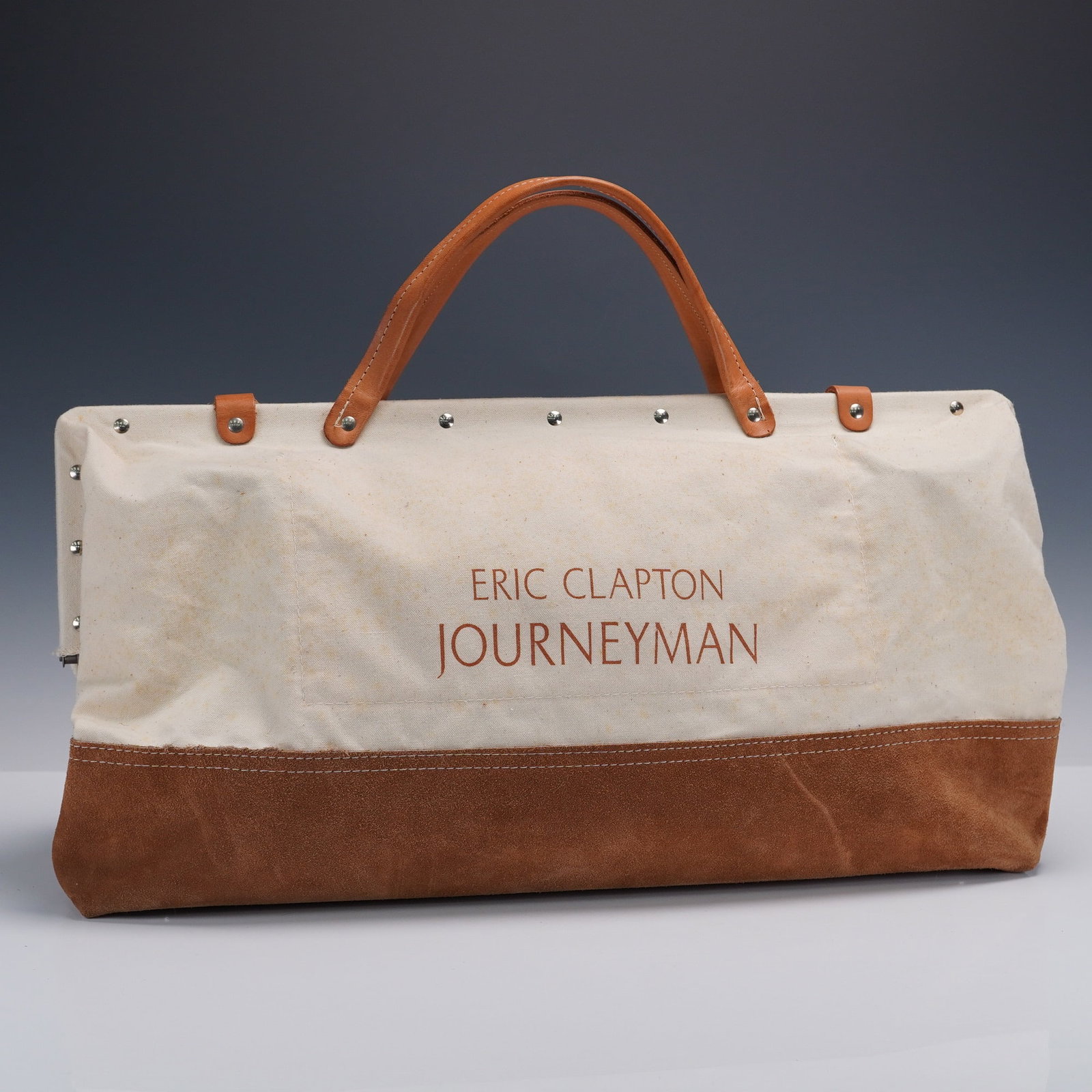 Eric Clapton Journeyman Promotional Canvas and Suede Duffle Bag: A distinctive promotional duffel bag commemorating Eric Clapton's Journeyman album, constructed in an elegant combination of heavy canvas and soft brown suede. This capacious hold all features a reinf