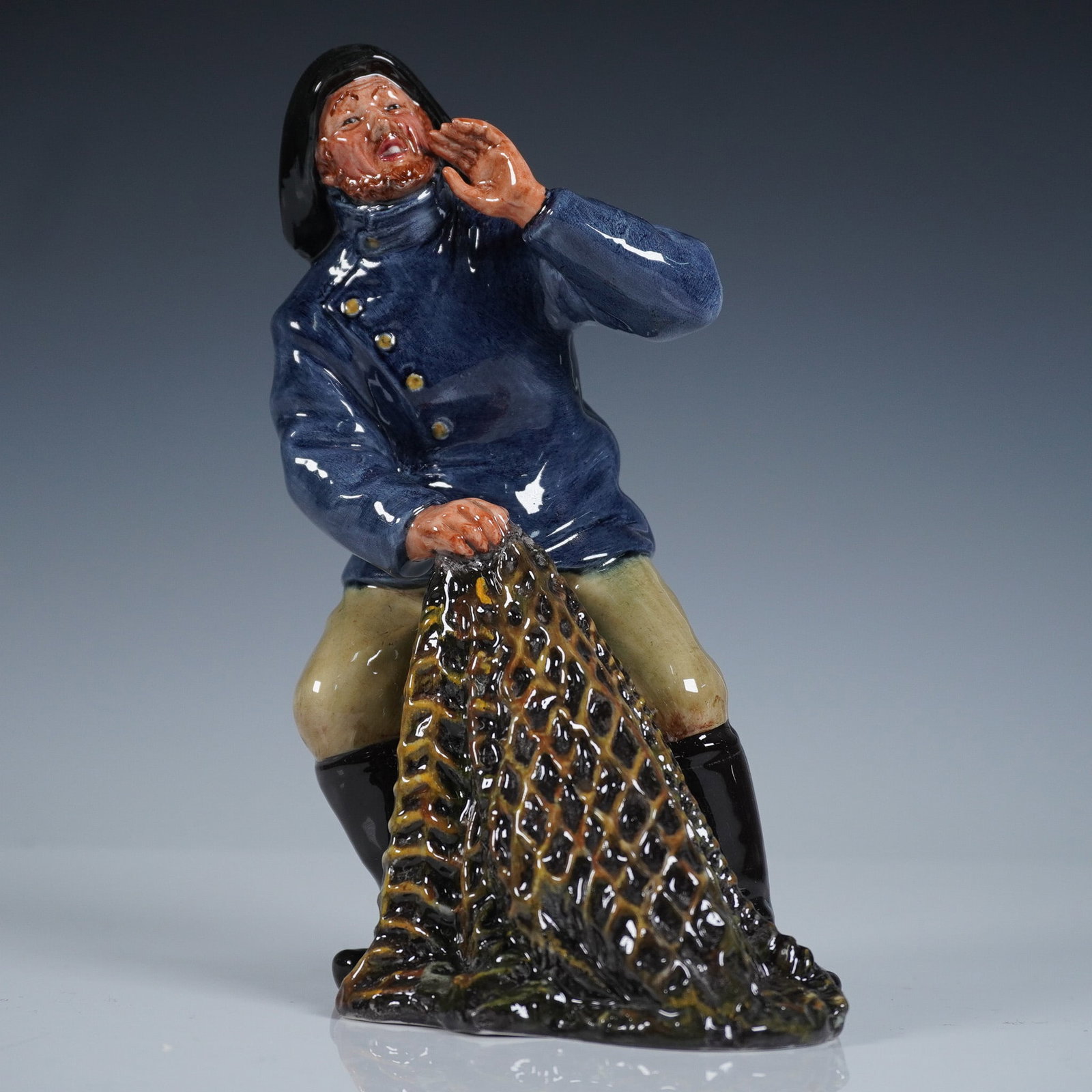 Royal Doulton Figurine, Sea Harvest HN2257: Glazed finish figure depicting a rugged fisherman hauling his net. Blue, black, and brown coloration; from the Sea Characters series. Royal Doulton backstamp. Artist: Mary Nicoll Issued: 1969 - 1976 D