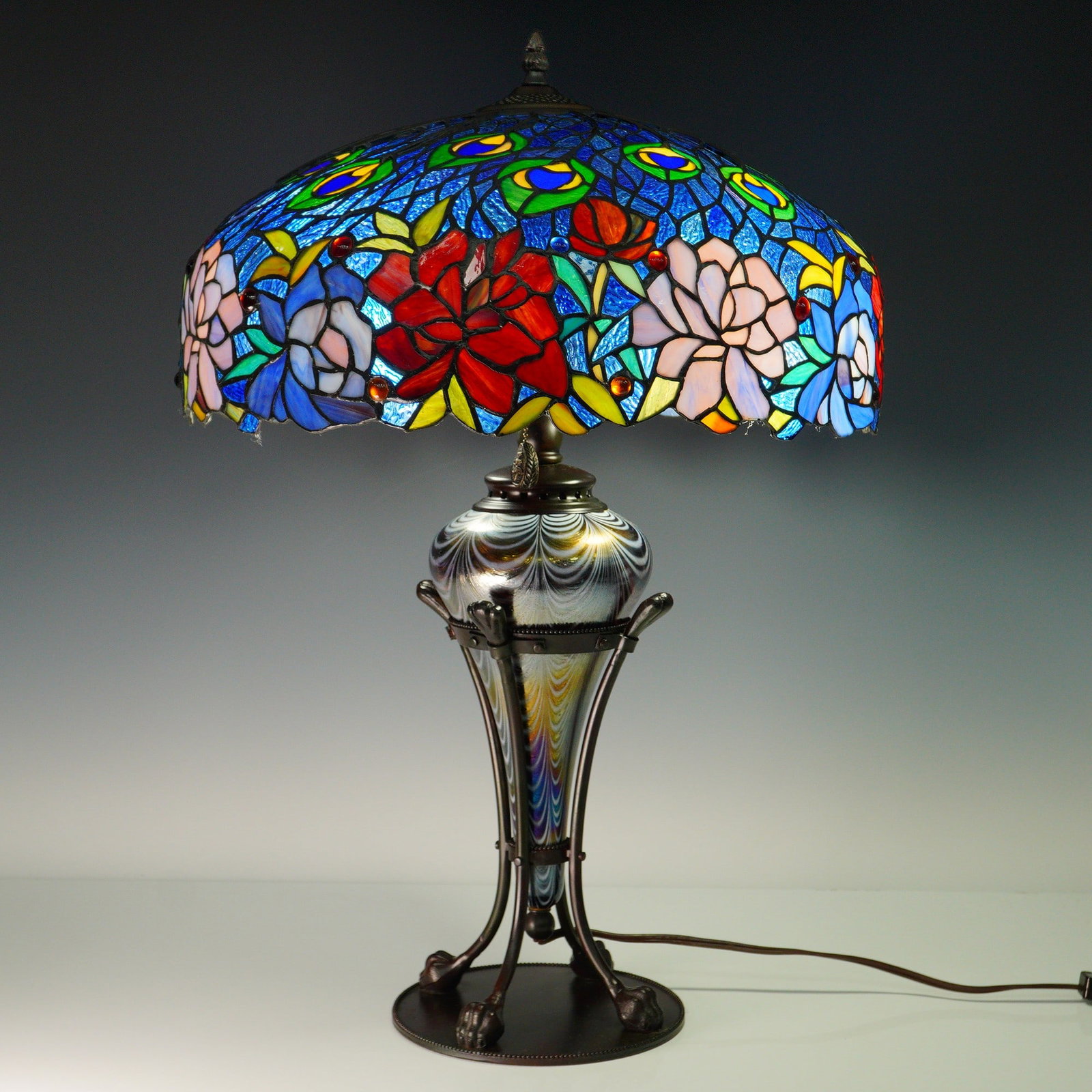 Vibrant Tiffany Style Leaded Glass Lamp with Iridized Art Glass and Bronze: An exceptional Tiffany style electric table lamp combining richly hued leaded glass and iridized art glass with intricate metalwork. The 18-inch diameter floral dome shade, 10 inches tall, is composed