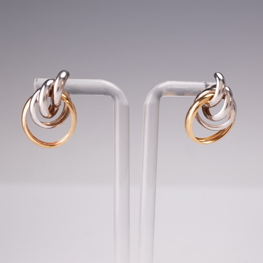 Vintage Style Two-Tone 14K Gold Knot Earrings: These stylish two-tone knot earrings feature interlocking hoops of polished 14K yellow gold and bright white gold, forming a sculptural and elegant design. Lightweight at under 1 gram in total, they a