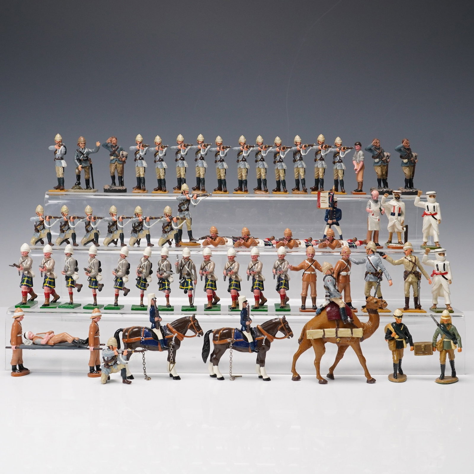 62pc British Colonial Military Miniature Figurines: 62-piece British Colonial Military miniature figurine set. Painted metal historical figures representing late 19th to early 20th century British colonial forces in various uniforms and poses. Includes