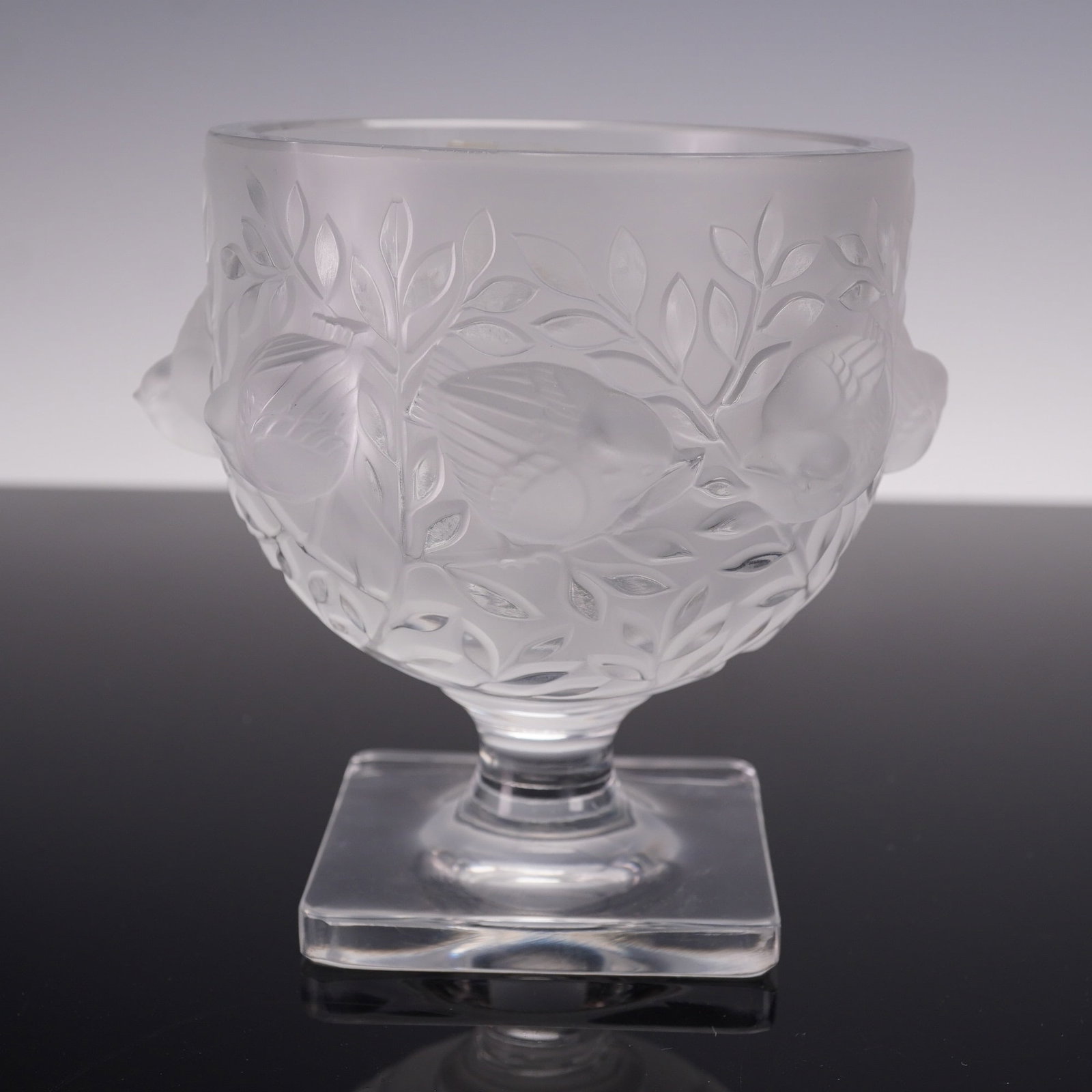 Lalique Elisabeth Footed Crystal Vase: Lalique France Elisabeth frosted crystal vase, decorated in relief with sparrows amidst leafy branches, raised on a square pedestal base. Etched Lalique France signature to the underside. Retains orig