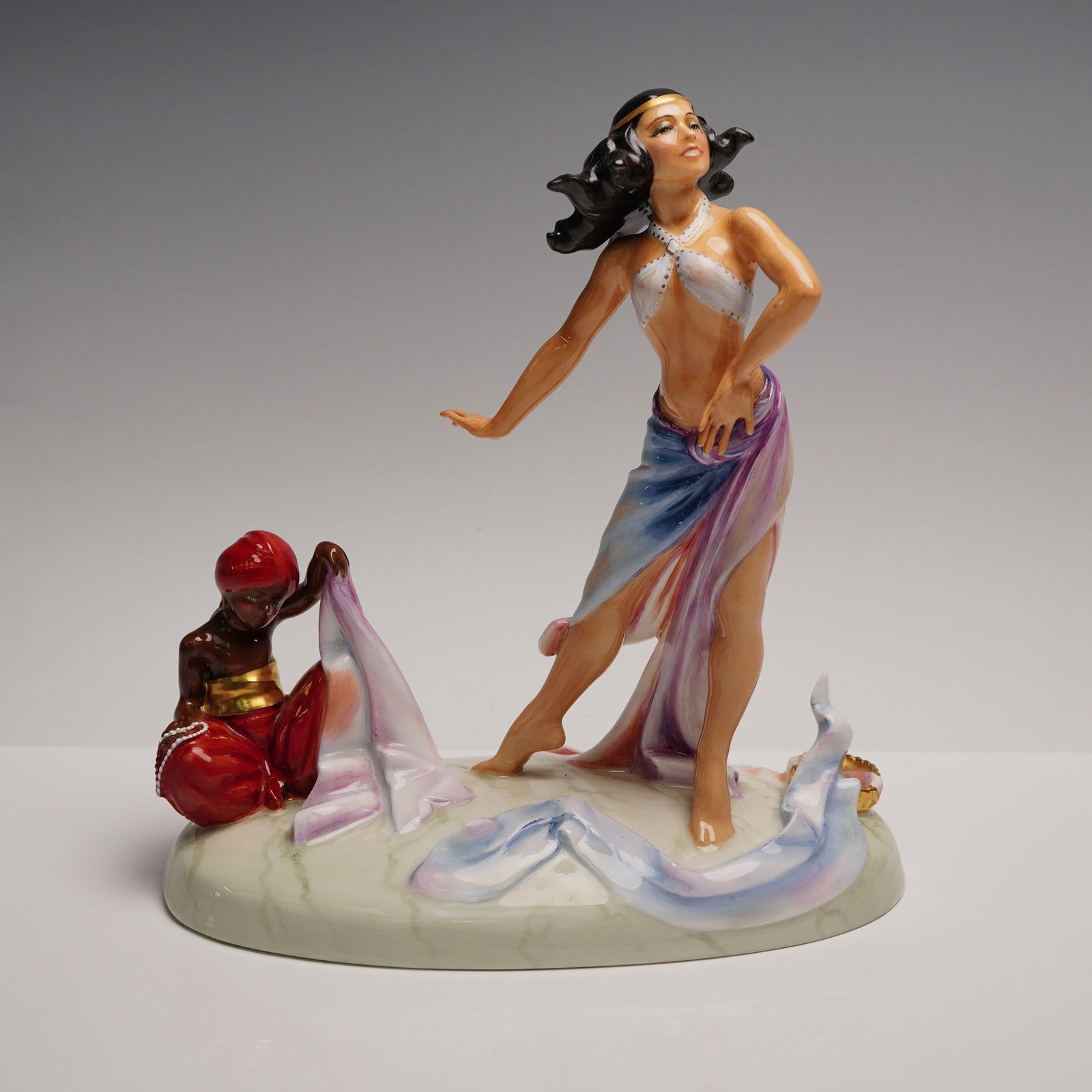 Royal Doulton Figurine, Salome HN3267: The figurine depicts the biblical figure Salome mid-dance, standing barefoot on a polished oval base. Her posture is theatrical, with one arm bent at the waist and the other extended, suggesting movem